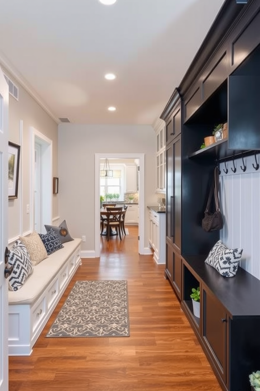 A spacious mudroom features a hidden storage bench seamlessly integrated into the wall. The bench is adorned with plush cushions and surrounded by built-in shelving for shoes and outdoor gear. Natural light floods the space through a large window, illuminating the warm wood tones and neutral color palette. Decorative hooks line the walls, providing a stylish solution for hanging coats and bags.