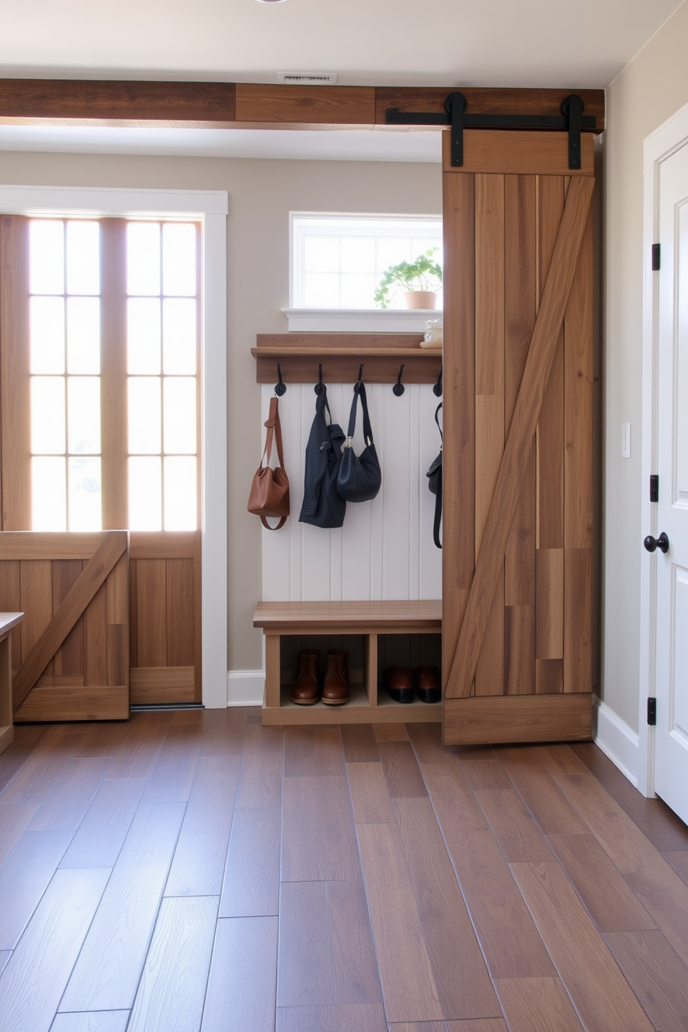 A spacious mudroom features sliding barn doors made of reclaimed wood that add rustic charm. Inside, a built-in bench with storage underneath is paired with hooks for coats and bags along the wall. The flooring is a durable tile that mimics the look of weathered wood, ensuring practicality and style. Natural light floods the space through a large window, creating an inviting atmosphere.