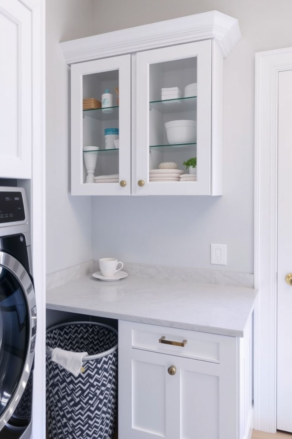 A bright and airy laundry room features glass front cabinets that elegantly showcase neatly arranged laundry supplies and decorative items. The cabinets are framed with sleek white trim, complementing the light gray walls and providing a modern touch to the space. The countertop beneath the cabinets is made of polished quartz, offering both functionality and style for folding clothes. A stylish laundry basket sits in the corner, adding a pop of color and enhancing the overall aesthetic of the room.