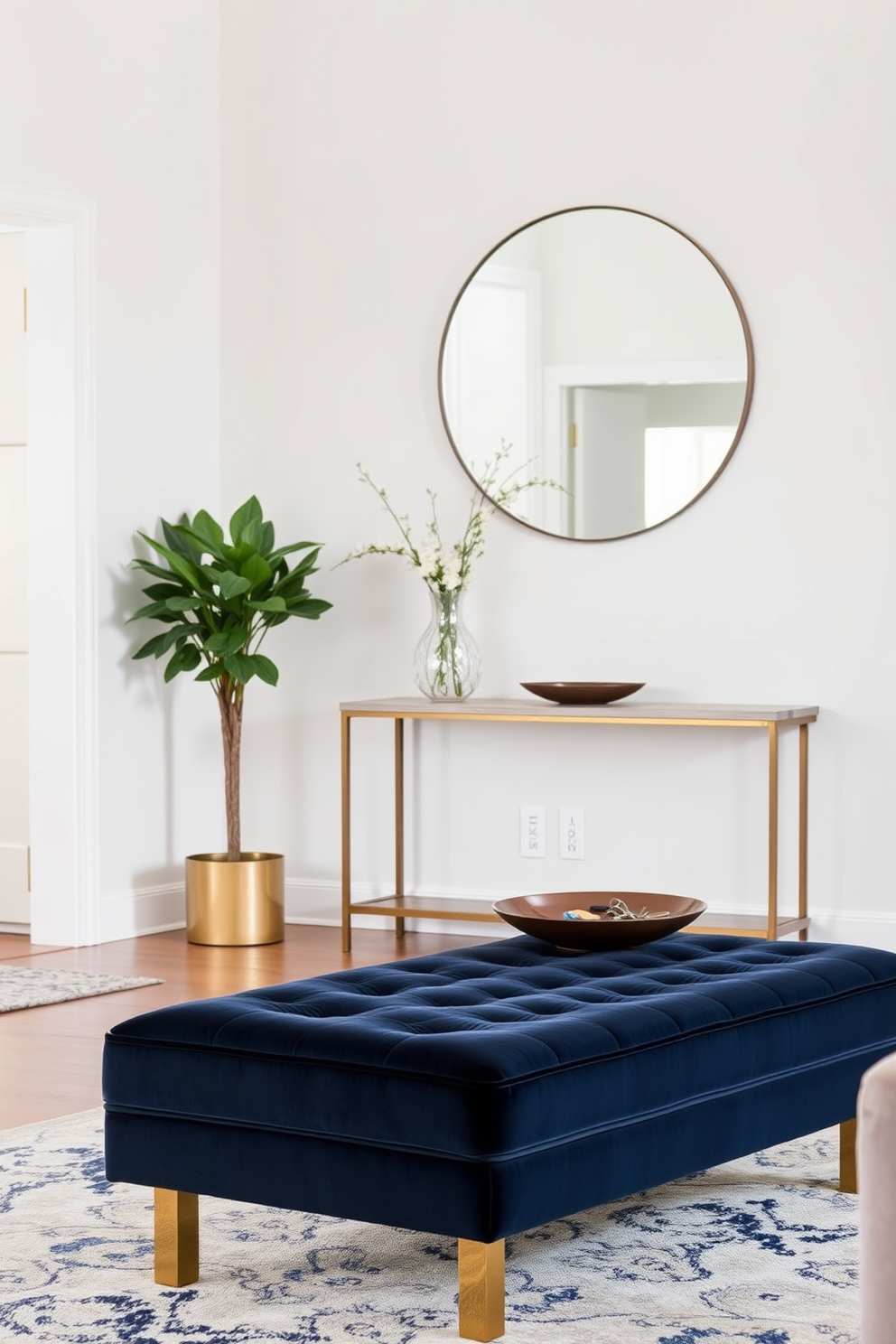 A stylish ottoman for extra seating is placed in the living room. It features a plush fabric in a rich navy blue, complemented by elegant gold legs that add a touch of luxury. In the entryway, a sleek console table stands against the wall. Above it, a large round mirror reflects natural light, while a decorative bowl holds keys and small items for convenience.