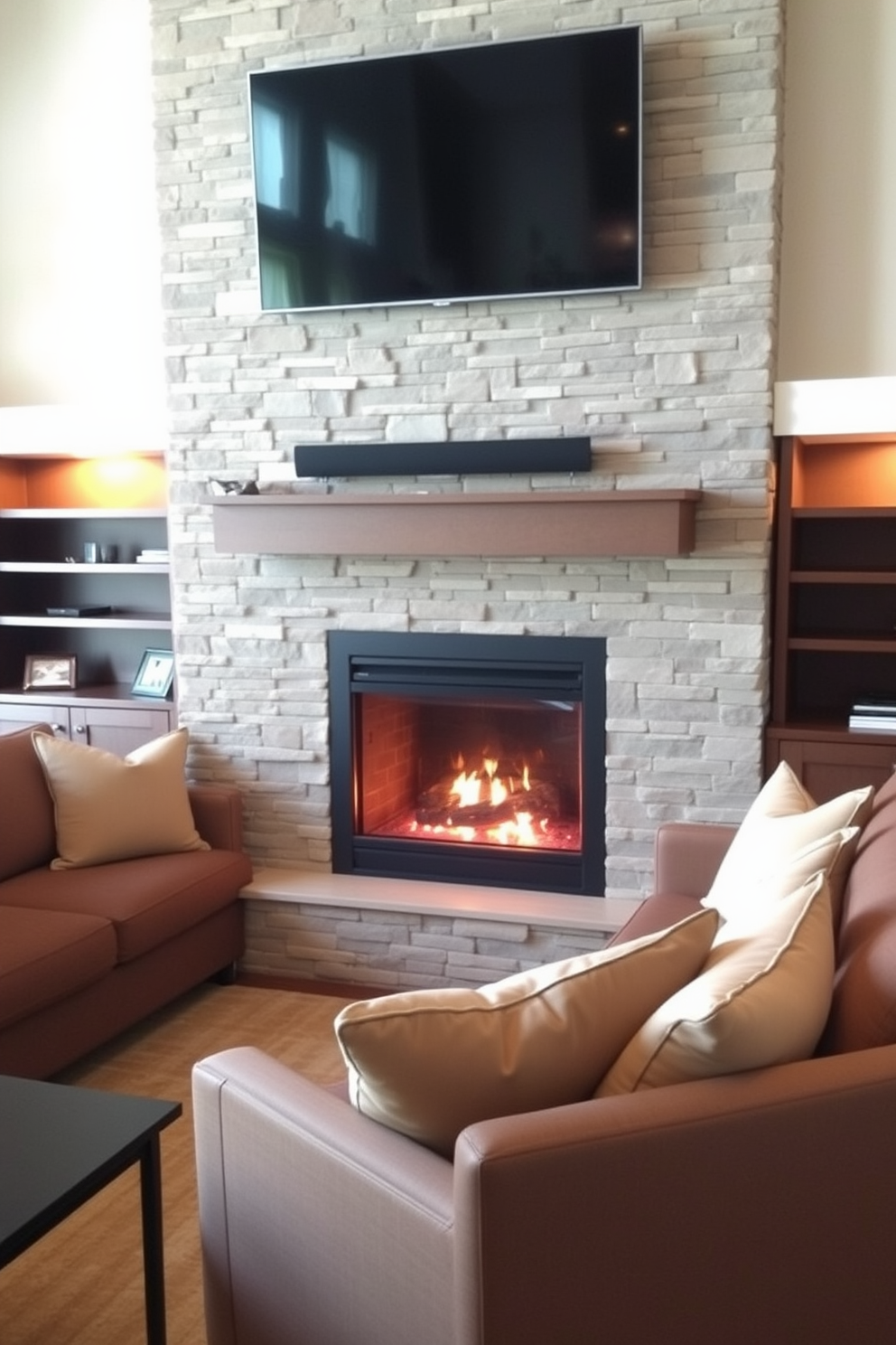 A cozy farmhouse living room features a rustic stone fireplace as the focal point, surrounded by built-in wooden shelves filled with books and decorative items. A comfortable sectional sofa in soft beige upholstery is arranged around a reclaimed wood coffee table, with a large flat-screen TV mounted above the fireplace for entertainment.