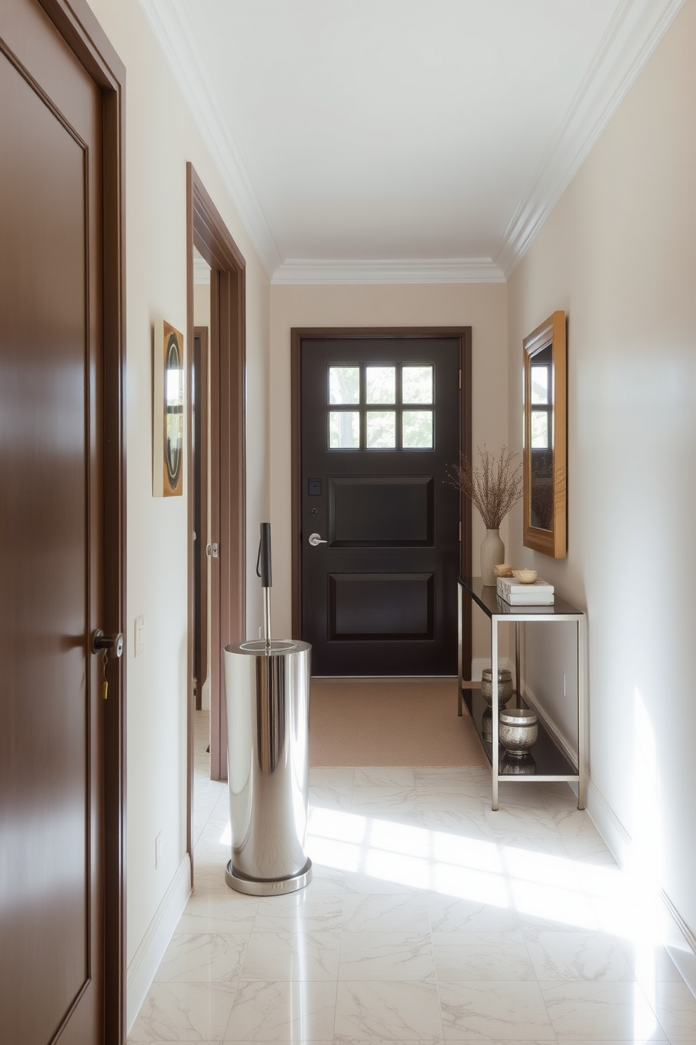 A long foyer with elegant design elements. There's a stylish umbrella stand made of polished metal positioned near the door, complementing the overall aesthetic of the space. The walls are adorned with soft neutral tones, creating a welcoming atmosphere. A sleek console table sits against one wall, topped with decorative items and a mirror reflecting natural light.