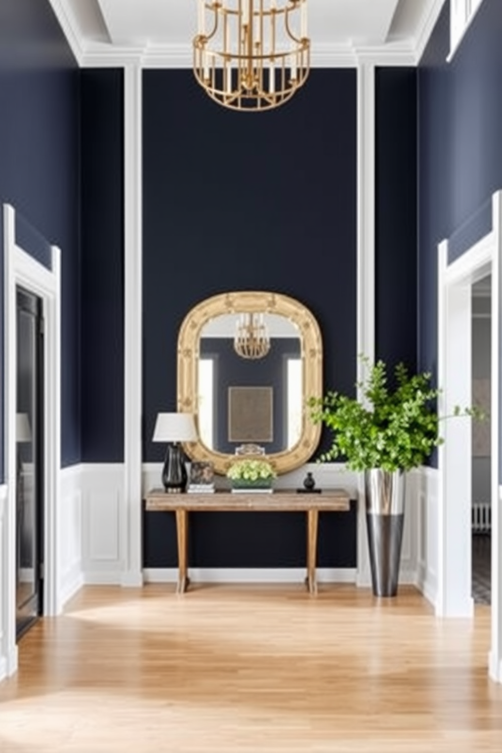 A long foyer with high ceilings and a dramatic entrance. The walls are painted in a deep navy blue, creating a striking contrast with the light hardwood flooring. A statement console table is placed against one wall, adorned with a large decorative mirror above it. Flanking the table are two tall, elegant vases filled with lush greenery, enhancing the welcoming atmosphere.