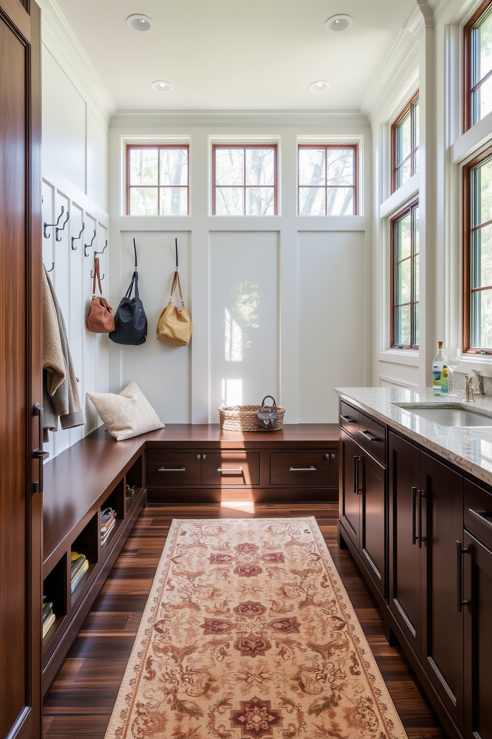 A functional drop zone for essentials featuring a built-in bench with storage underneath. The walls are adorned with hooks for coats and bags, and a stylish area rug adds warmth to the space. Luxury mudroom design ideas include elegant cabinetry with a rich wood finish and a polished stone countertop. Ample natural light floods the room through large windows, enhancing the inviting atmosphere.