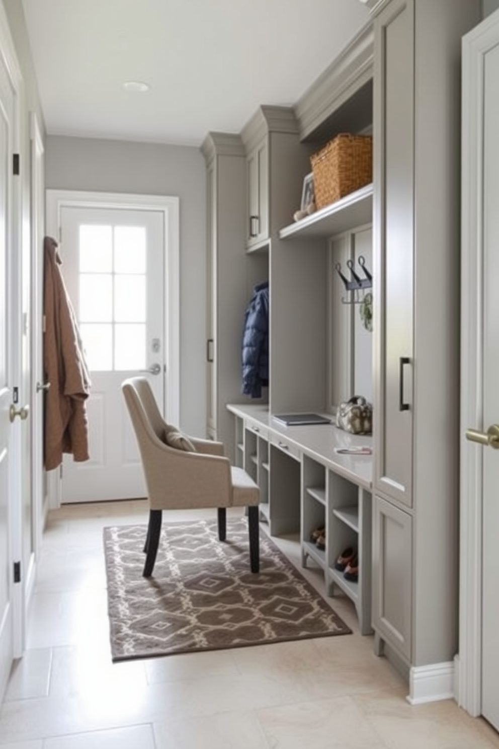 A stylish mudroom featuring a small desk area designed for functionality and elegance. The space includes built-in cabinetry for storage, a comfortable chair, and a sleek desk that complements the overall aesthetic. The walls are adorned with a soft gray paint, enhancing the bright natural light that floods the room. A patterned area rug lies beneath the desk, while hooks and cubbies provide organization for coats and shoes.