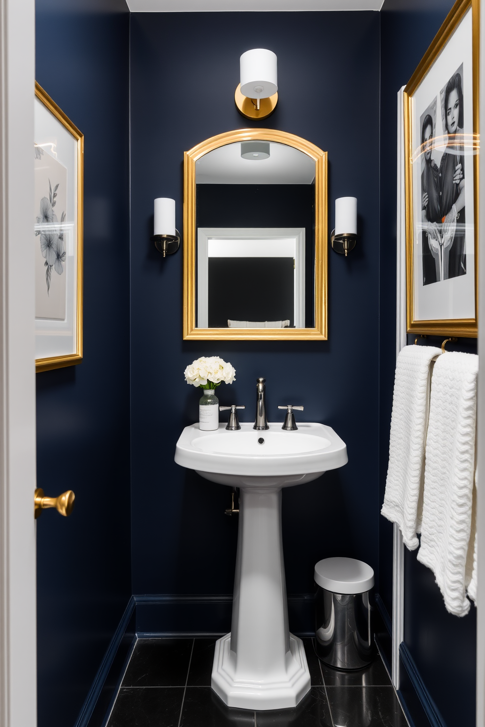 Deep navy walls create a dramatic backdrop while white accents add a touch of elegance. The space features a sleek white pedestal sink and a stylish gold-framed mirror, enhancing the luxurious feel of the powder room.