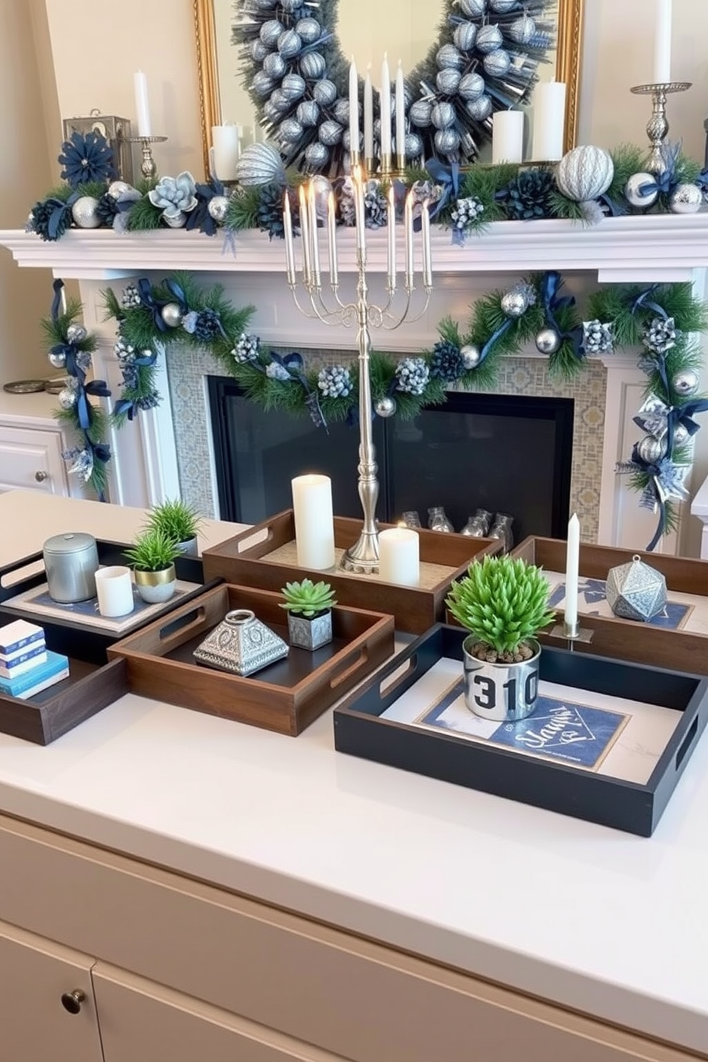 A collection of decorative trays in varying sizes and materials is arranged on a sleek countertop. Each tray holds curated items such as candles, small plants, and stylish coasters, creating an organized yet aesthetically pleasing display. The mantel is adorned with festive Hanukkah decorations, featuring a beautiful menorah at the center. Surrounding the menorah are blue and silver accents, including garlands, candles, and decorative dreidels, adding a warm and inviting atmosphere to the room.