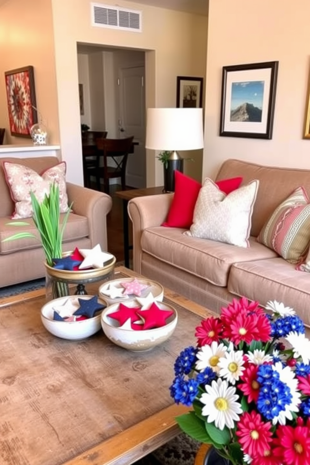 A cozy apartment living room adorned with decorative bowls filled with stars. The bowls are placed on a rustic wooden coffee table, surrounded by plush seating and soft throw pillows in red, white, and blue hues. The walls are painted a light beige, creating a warm backdrop for the festive decor. A cheerful arrangement of fresh flowers in patriotic colors sits nearby, enhancing the Memorial Day theme throughout the space.