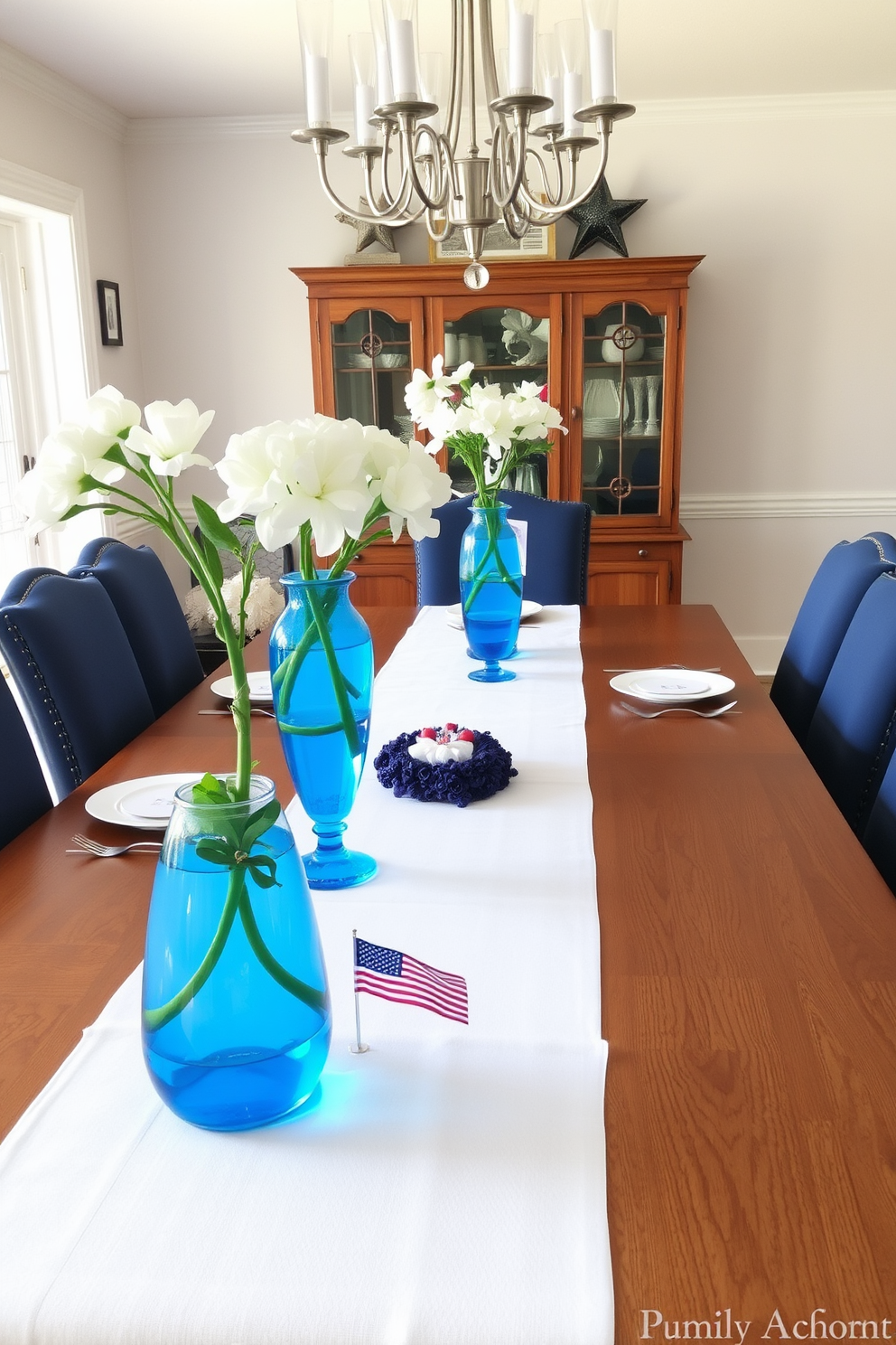 A modern dining room setting featuring clear glass plates on a sleek wooden table. The table is adorned with a simple yet elegant centerpiece of fresh flowers and candles for a festive Memorial Day atmosphere.