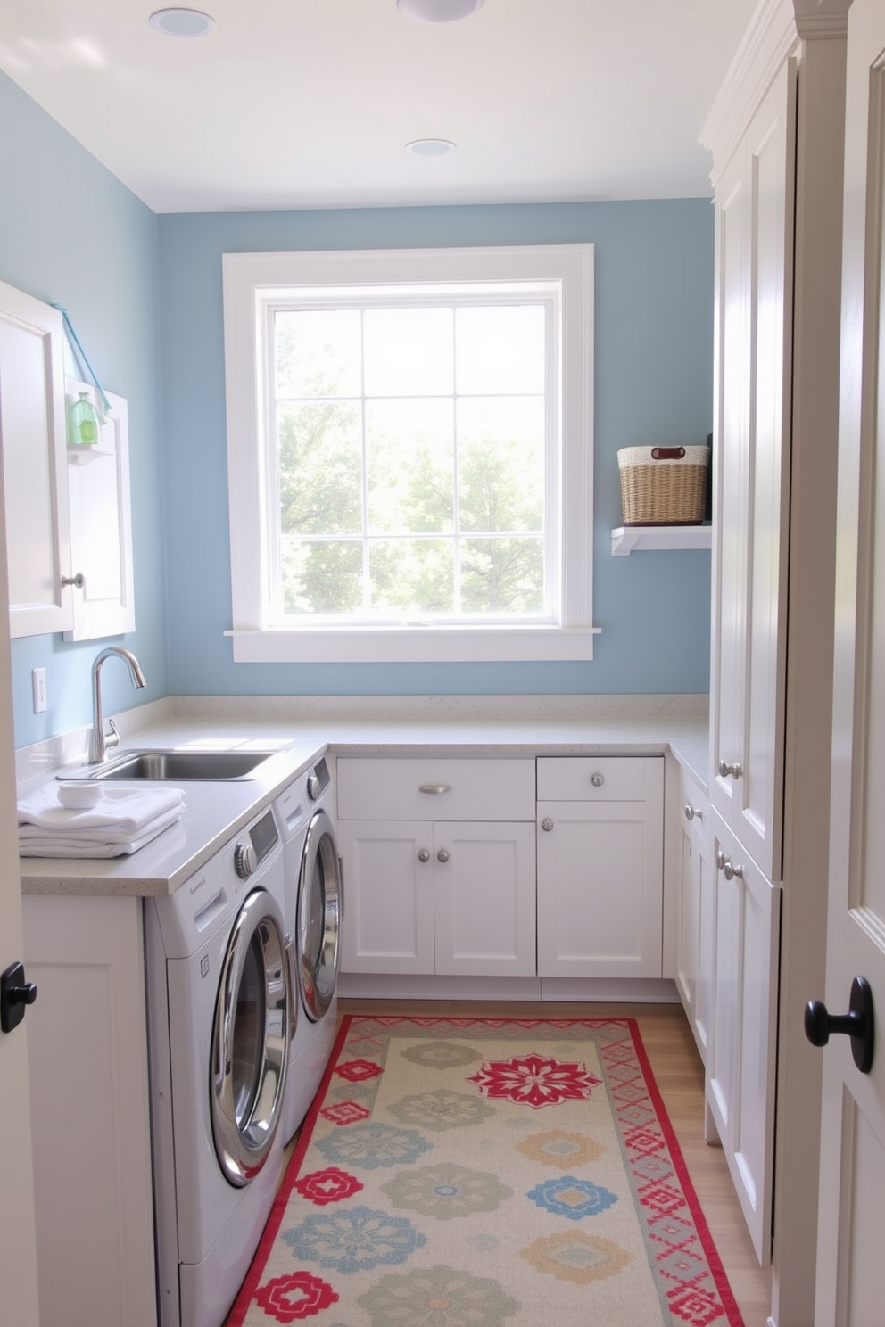 A bright and airy laundry room featuring a spacious countertop for folding clothes and a stylish washer and dryer set. The walls are painted in a soft blue hue, complemented by white cabinetry that provides ample storage space. A large window allows natural light to flood the room, enhancing the cheerful atmosphere. A colorful, patterned rug is placed underfoot to add comfort and style, while decorative baskets on shelves keep laundry essentials organized.