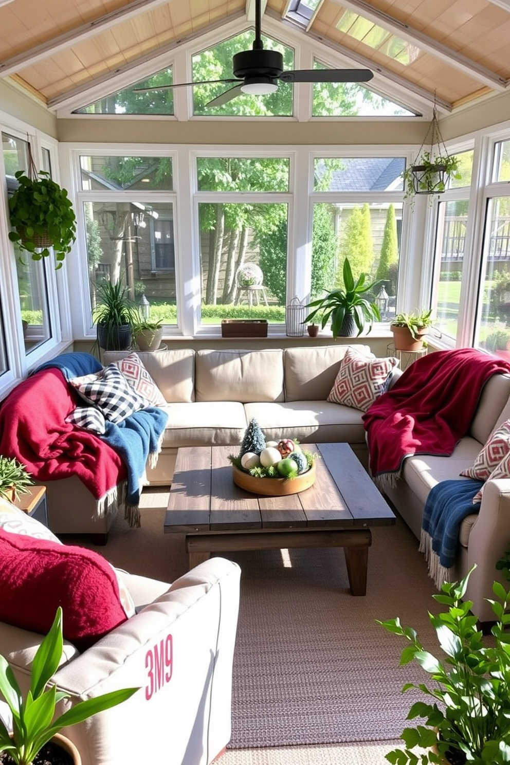 A sunroom filled with natural light featuring cozy blankets in red and blue draped over a comfortable sectional sofa. Potted plants in the corners add a touch of greenery, while a rustic coffee table sits in the center adorned with seasonal decorations.