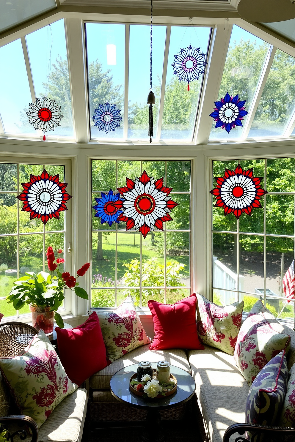 A sunroom filled with natural light showcases vibrant sun catchers in red, white, and blue, reflecting the patriotic spirit of Memorial Day. The space features comfortable seating adorned with seasonal cushions, creating a welcoming atmosphere for relaxation and celebration.