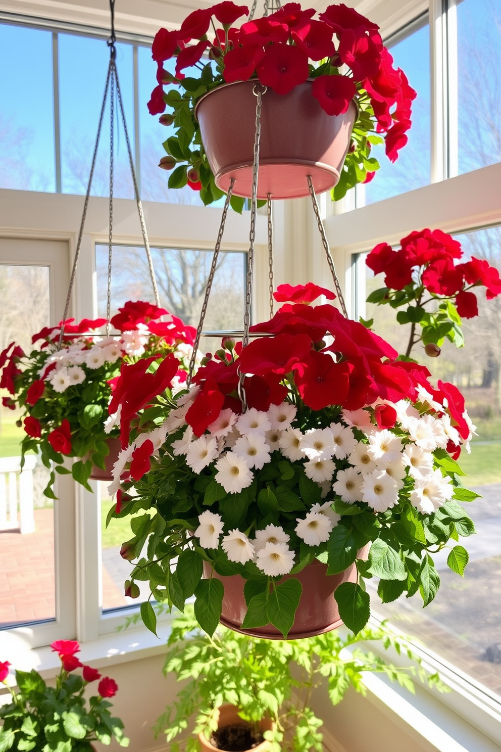 Hanging planters filled with vibrant red and white flowers create a festive atmosphere in the sunroom. The sunlight filters through the large windows, illuminating the cheerful blooms and enhancing the inviting space.