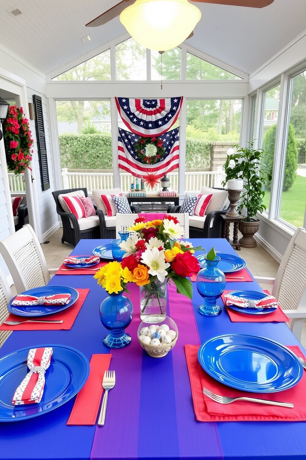 A vibrant summer-themed table setting for a festive dining experience. The table is adorned with bright blue plates, colorful napkins, and cheerful centerpieces featuring fresh flowers. A sunroom decorated for Memorial Day with red, white, and blue accents. The space includes comfortable seating, patriotic throw pillows, and a table displaying seasonal decor items.