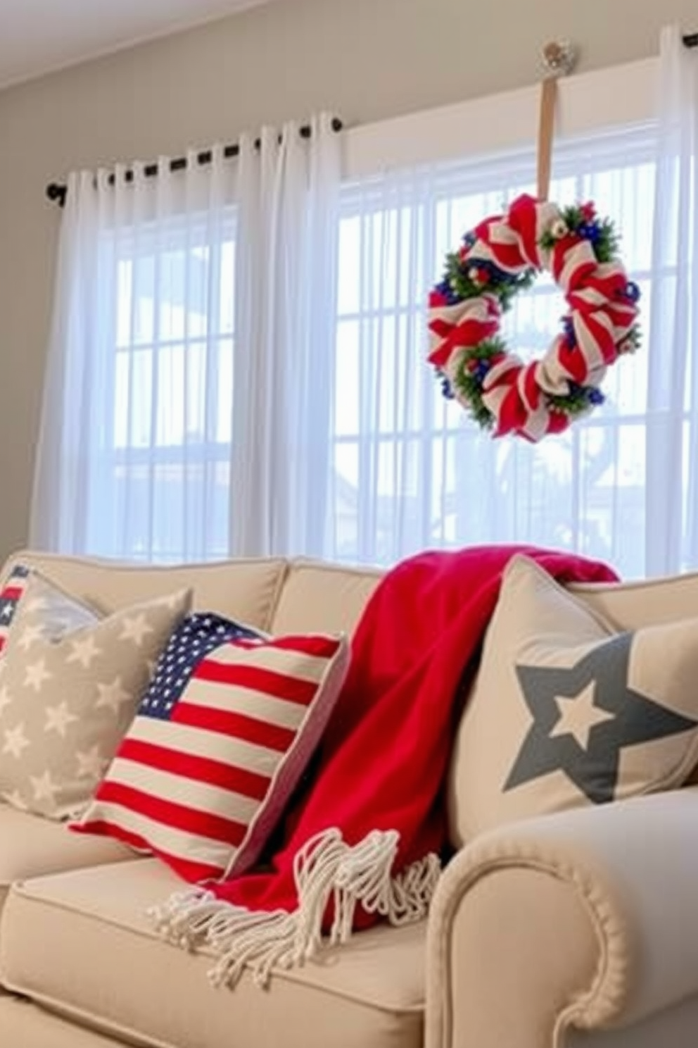 Create a cozy living room setting featuring decorative pillows adorned with stars and stripes to celebrate Memorial Day. The pillows are arranged on a plush sofa, complemented by a vibrant throw blanket draped casually over the armrest. In the background, large windows are dressed with sheer white curtains that allow natural light to filter in. A patriotic-themed wreath hangs on the window, adding a festive touch to the overall decor.