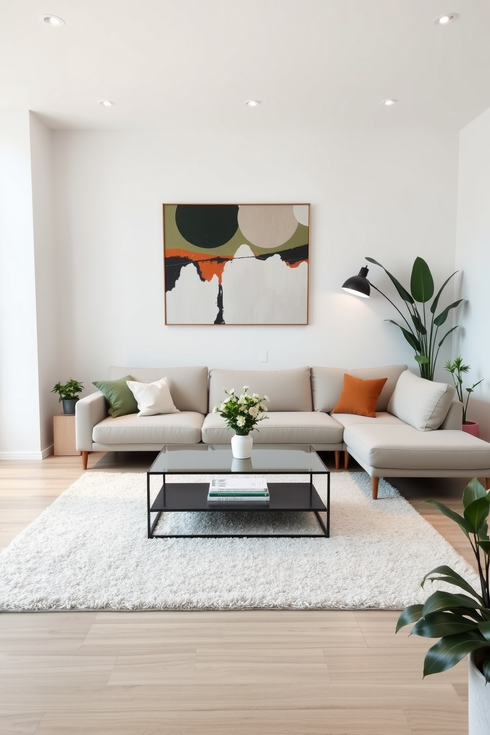 A minimalist family room features a light gray sectional sofa paired with a sleek glass coffee table. The walls are painted in a soft white, and a large abstract painting adds a pop of color above the sofa. Soft lighting creates a cozy ambiance with recessed lights and a stylish floor lamp in the corner. A plush area rug anchors the space, while potted plants bring a touch of nature indoors.