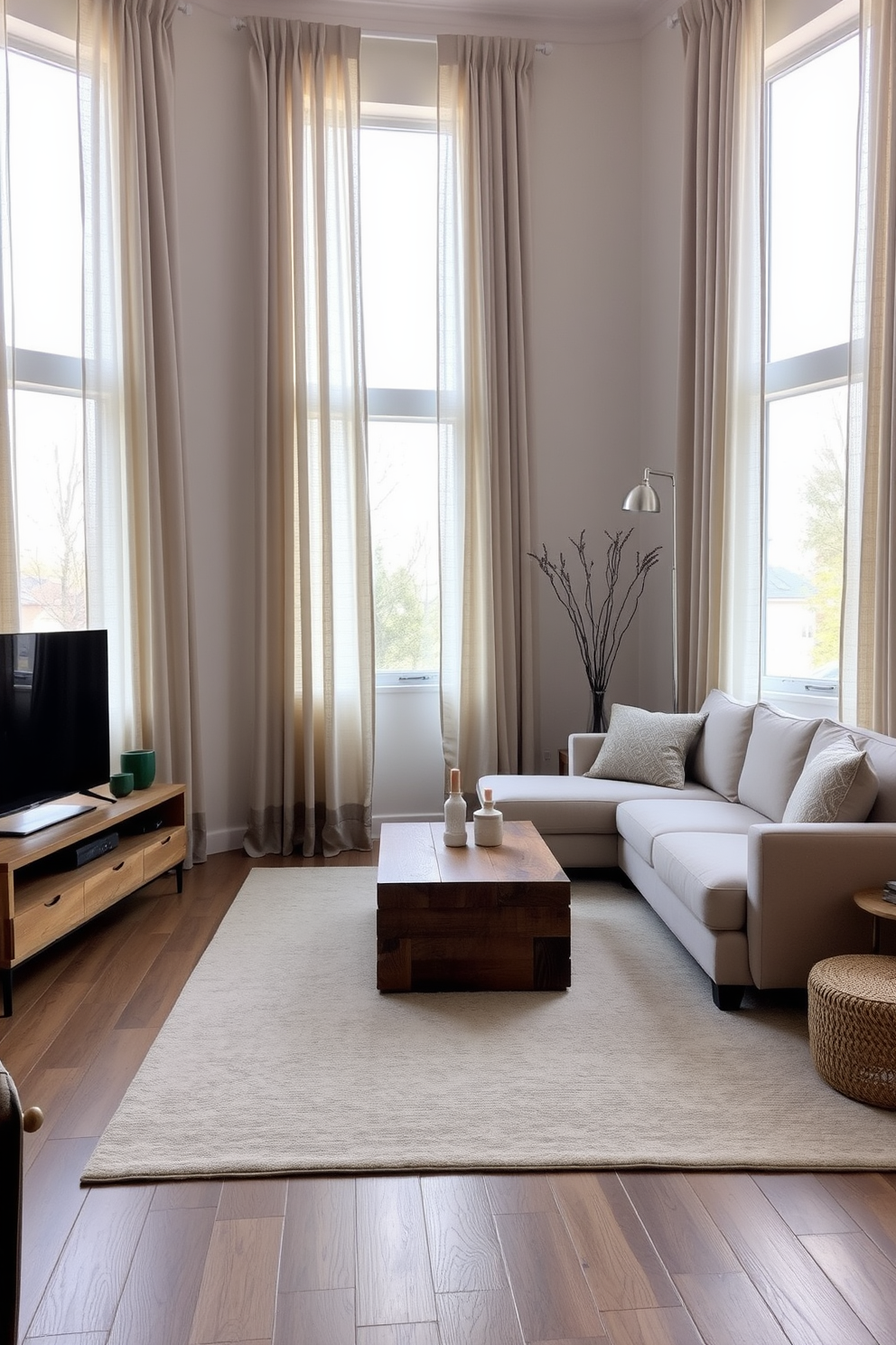 A minimalist family room featuring neutral-toned curtains that softly frame large windows allowing natural light to filter in. The space includes a sleek sectional sofa in a light beige fabric paired with a simple coffee table made of reclaimed wood. On one side, a low-profile entertainment unit holds a flat-screen TV while maintaining a clean aesthetic. A plush area rug in muted tones anchors the seating area, creating a cozy and inviting atmosphere.