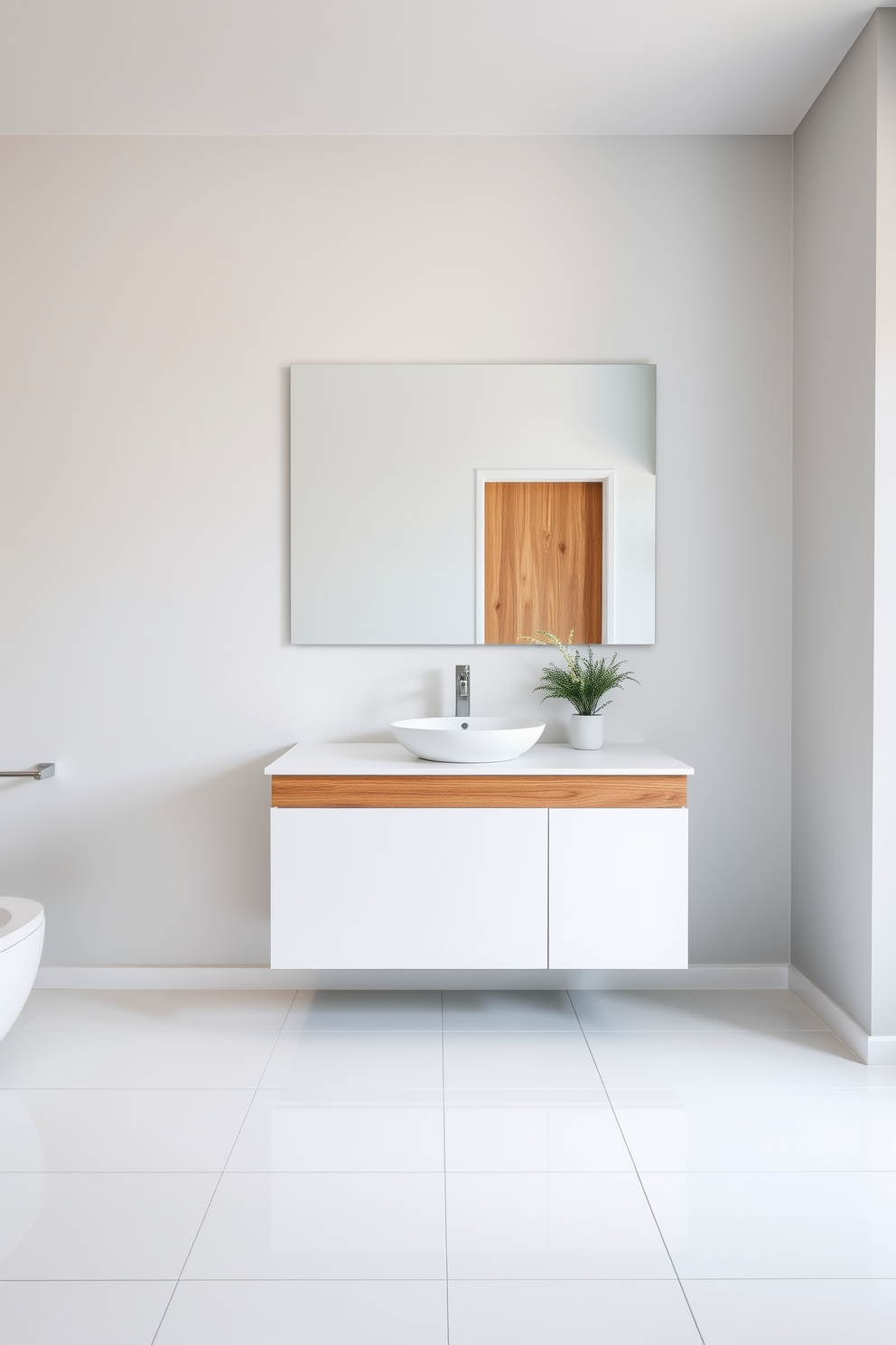 A minimalist white vanity with natural wood accents sits against a light gray wall. The countertop is adorned with a sleek vessel sink and a brushed nickel faucet, creating an elegant contrast. Large format white tiles cover the floor, enhancing the spacious feel of the modern bathroom. A simple potted plant adds a touch of greenery, while a large frameless mirror reflects the serene atmosphere.