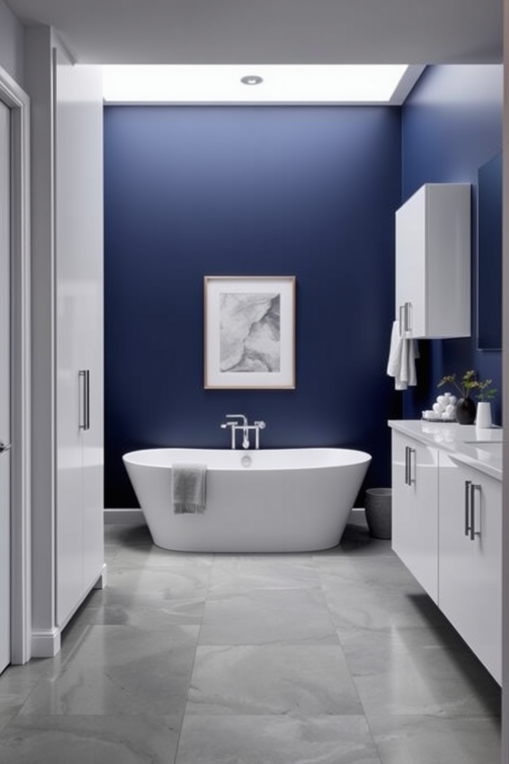 A bold accent wall painted in a rich navy blue creates a striking focal point in the modern bathroom. The sleek white fixtures and minimalist cabinetry complement the dramatic backdrop, enhancing the overall aesthetic. Large format tiles in a soft gray line the floor, providing a contemporary contrast to the dark wall. A freestanding bathtub sits elegantly against the accent wall, adorned with stylish accessories for a luxurious touch.