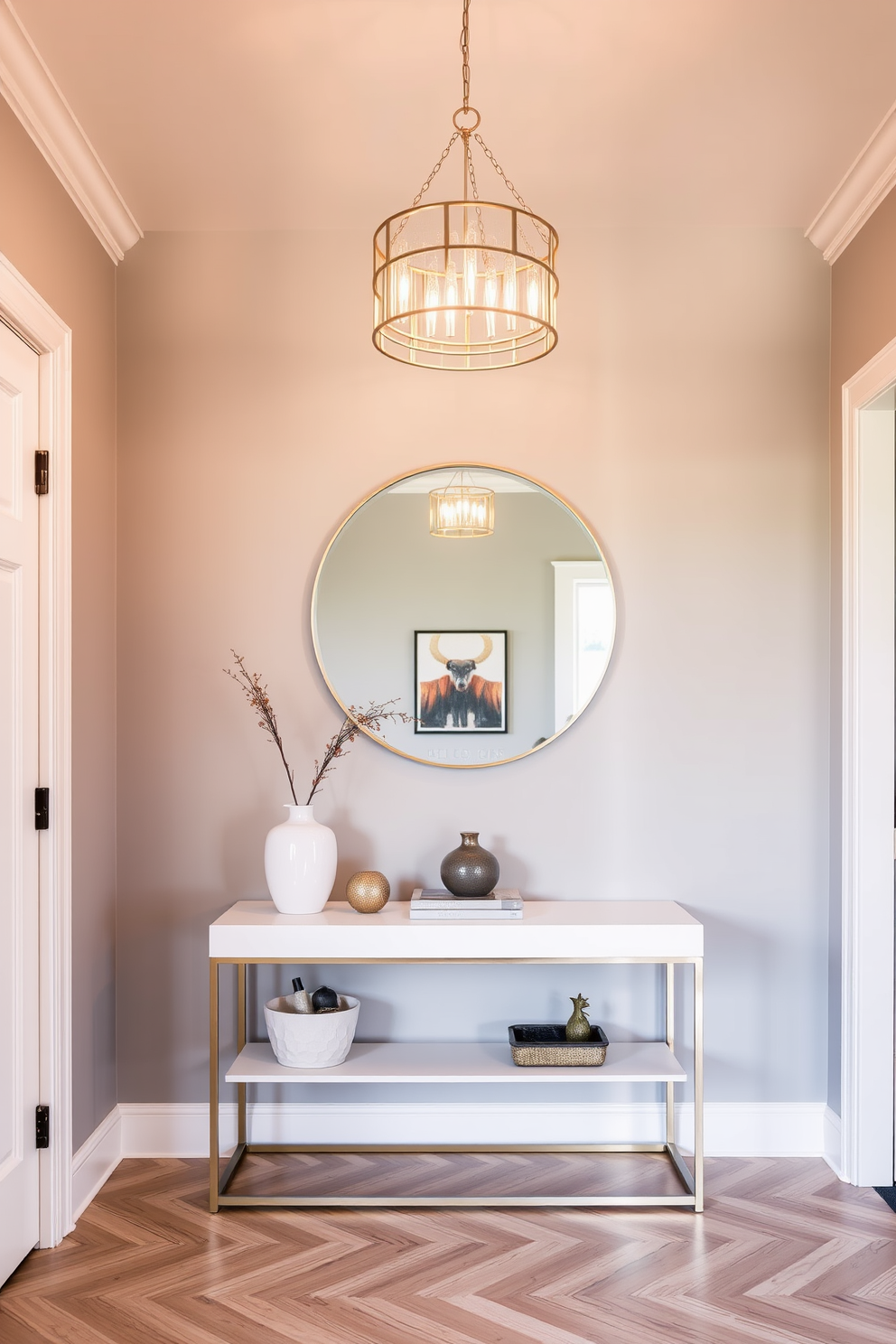 A chic lighting fixture hangs elegantly above the entryway creating a warm and inviting atmosphere. The walls are painted in a soft gray, complementing a sleek console table adorned with decorative accents. The floor features a herringbone pattern in light wood, enhancing the modern aesthetic. A large round mirror is mounted above the console, reflecting natural light and making the space feel larger.