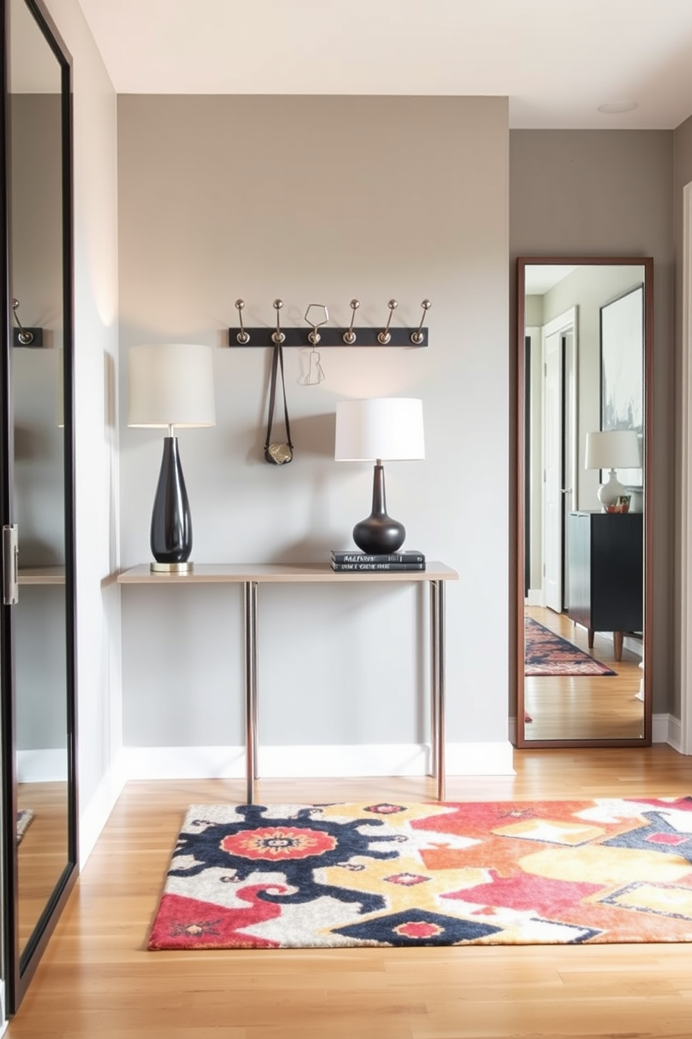 A modern foyer features a sleek console table against the wall with a stylish lamp on top. Unique coat hooks are mounted above the table, designed in various geometric shapes to add an artistic touch. The flooring is a combination of polished wood and a vibrant area rug that adds warmth to the space. Large mirrors are placed strategically to enhance light and create an inviting atmosphere.