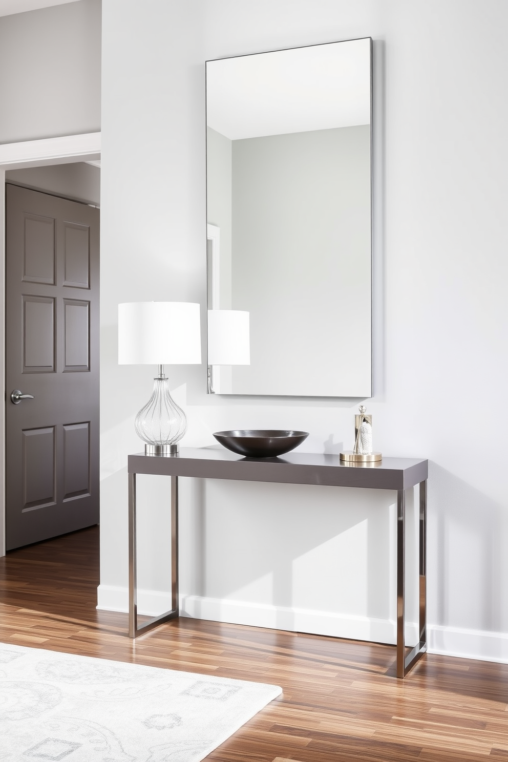 A sleek console table stands against the wall in a modern foyer. It features clean lines and a glossy finish, complemented by a stylish lamp and a decorative bowl on top. The walls are painted in a soft gray hue, enhancing the airy feel of the space. A large mirror hangs above the console, reflecting light and making the foyer feel more expansive.