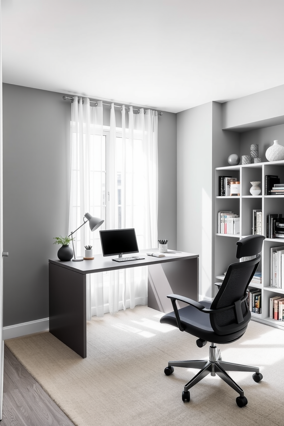 A sleek modern home office features a monochromatic color scheme with varying shades of gray. The walls are painted in a soft dove gray, complemented by a charcoal gray desk and matching ergonomic chair. Natural light floods the space through a large window adorned with sheer white curtains. A minimalist bookshelf in a light gray finish stands against one wall, filled with neatly organized books and decorative items.