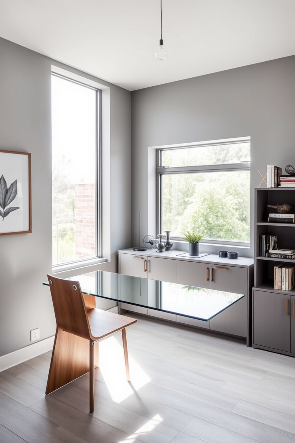 A modern home office design that maximizes small space efficiency. The room features a sleek glass desk paired with a warm wooden chair, creating a striking contrast between materials. The walls are painted in a soft gray, enhancing the sense of openness. A large window allows natural light to flood the room, complemented by minimalist shelving that showcases decorative items and books.