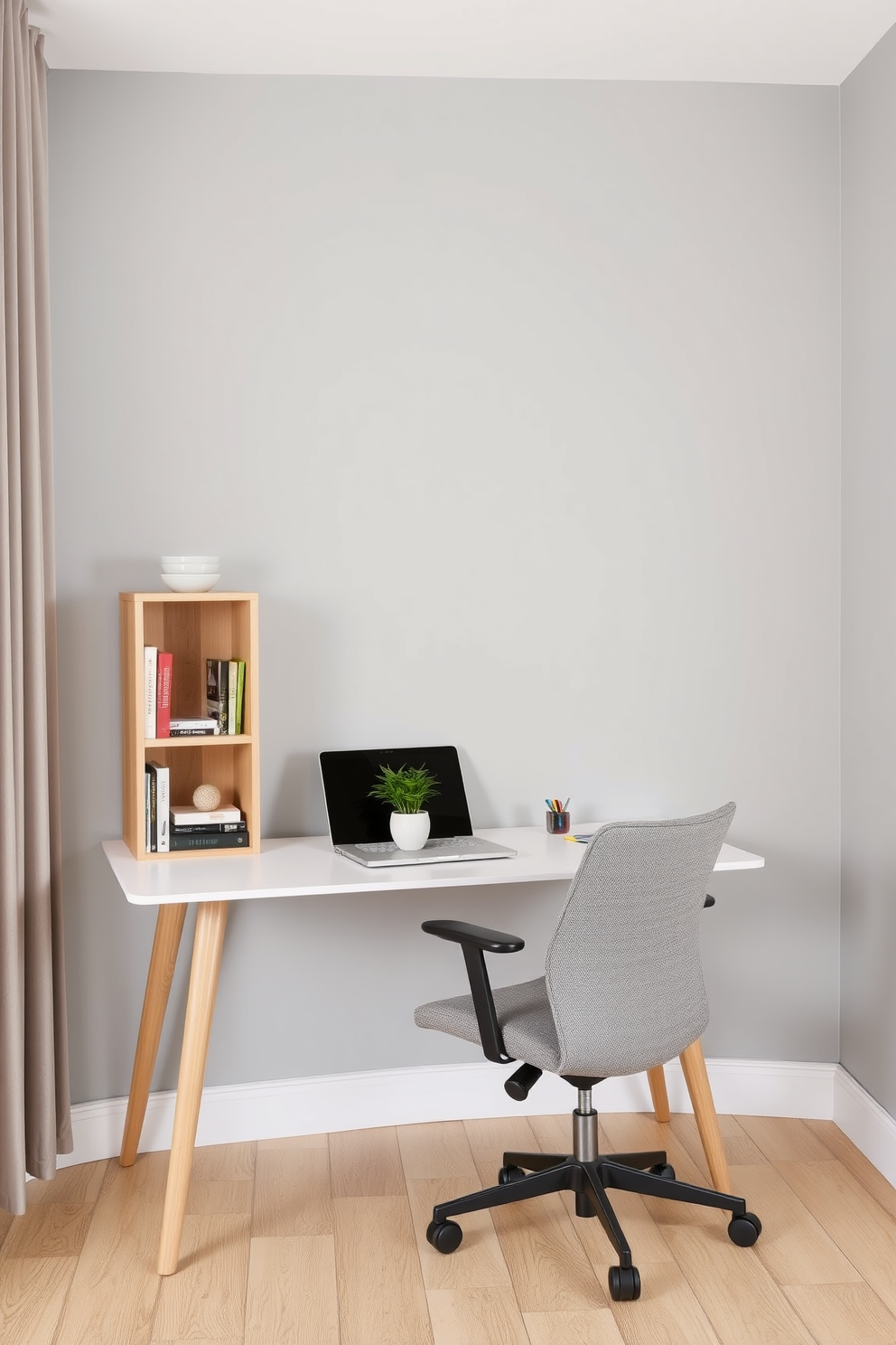 A modern home office designed for small spaces features a sleek desk positioned against a light gray wall. A small bookshelf made of natural wood stands beside the desk, filled with neatly arranged books and decorative items. The office chair is ergonomic and upholstered in a soft fabric, providing comfort for long work hours. A simple potted plant sits on the desk, adding a touch of greenery to the minimalist decor.