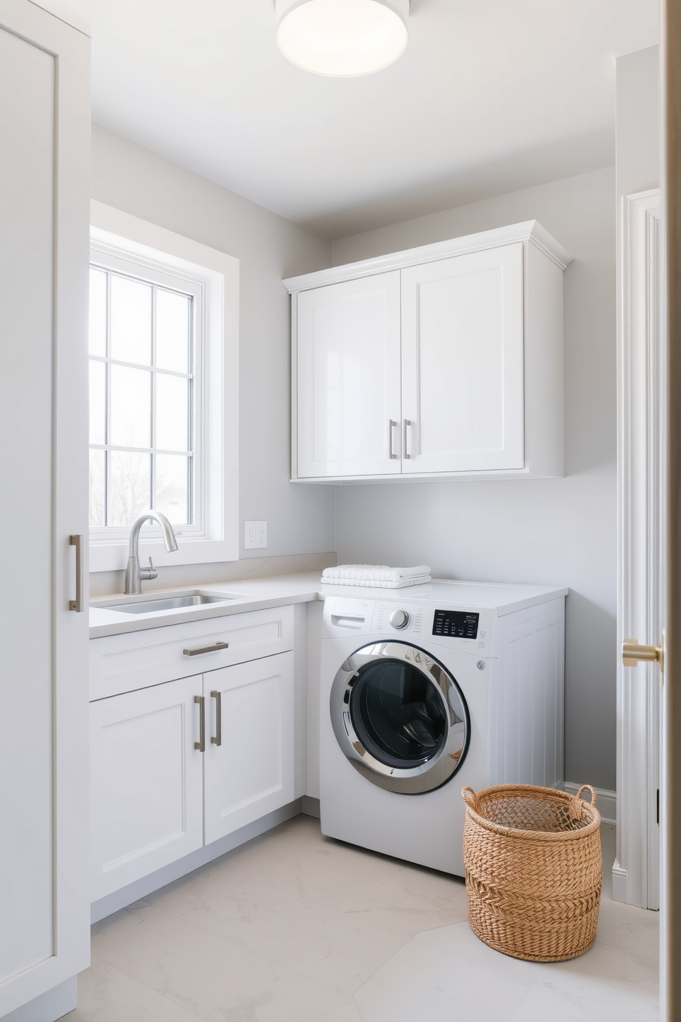 A modern laundry room features sleek cabinetry in a crisp white finish with minimalist hardware. The space includes a stackable washer and dryer with a clean countertop above for folding clothes. Natural light floods the room through a large window, illuminating the pale gray walls. A simple woven basket sits on the floor, providing a stylish storage solution for laundry essentials.