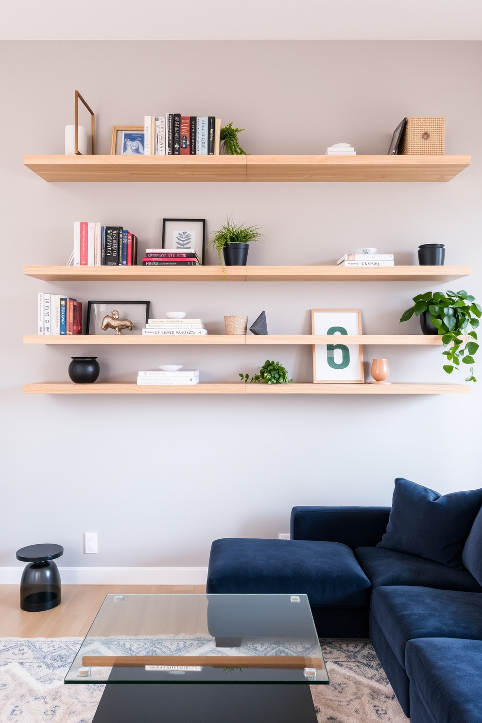 A modern living room features floating shelves that provide stylish storage solutions. The shelves are made of light wood and are adorned with decorative books, plants, and art pieces. The walls are painted in a soft gray, creating a calming backdrop. A plush sectional sofa in a rich navy blue complements the space, paired with a sleek glass coffee table at the center.