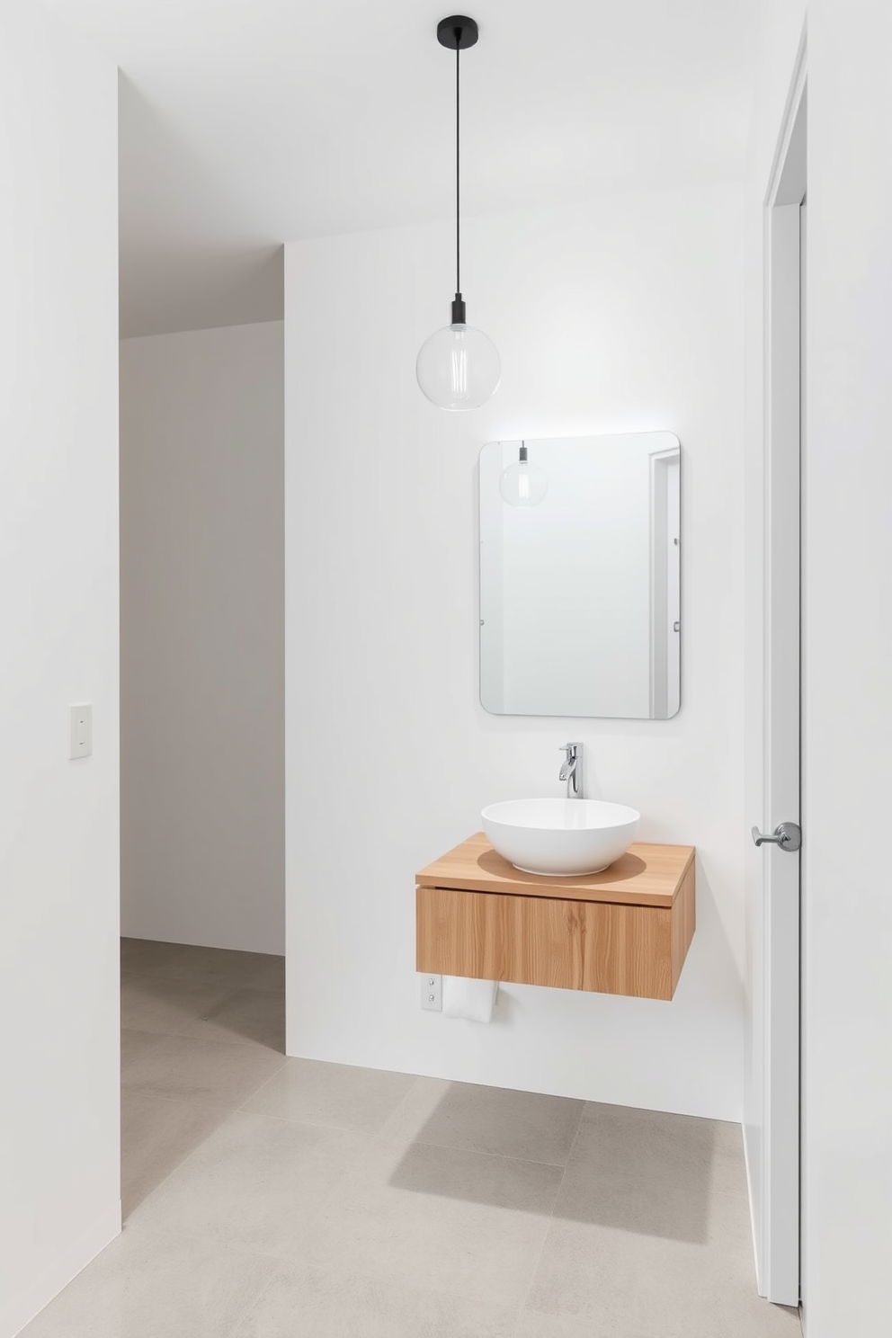 A minimalist powder room featuring sleek lines and a neutral color palette. The walls are painted in soft white, and the flooring is a light grey stone. A floating vanity with a single, round sink is positioned against the wall, complemented by a large frameless mirror. Simple pendant lighting hangs above, adding a touch of elegance to the serene atmosphere.