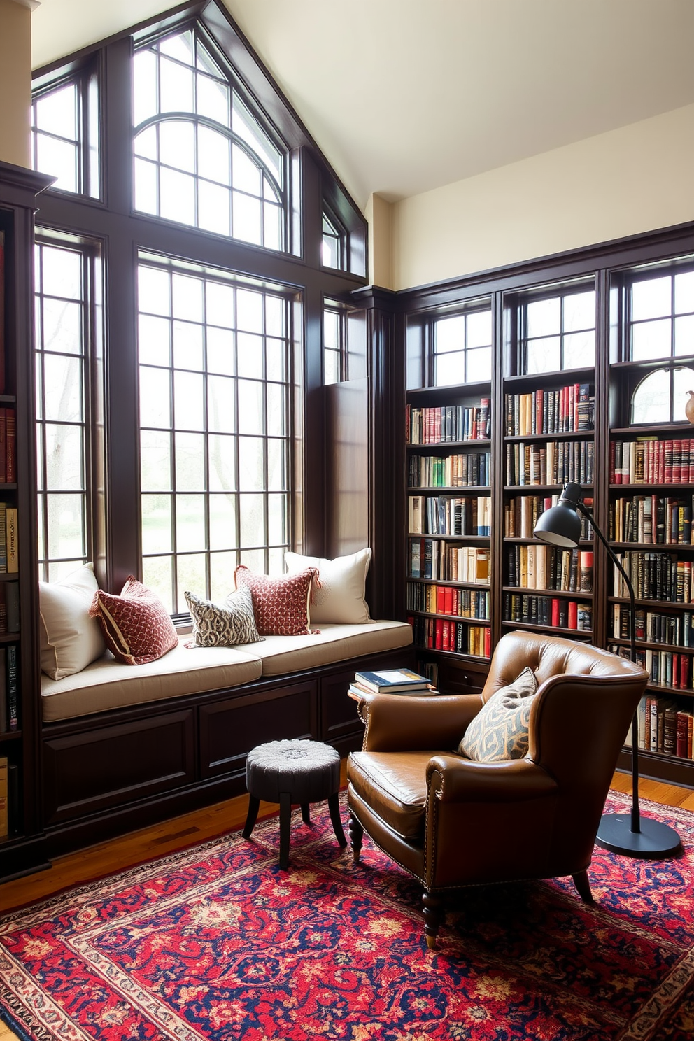 A cozy home library featuring large windows that allow natural light to flood the space. Deep window seats are adorned with plush cushions, creating a perfect reading nook. The walls are lined with dark wooden bookshelves filled with an extensive collection of books. A rich, textured rug anchors the seating area, complemented by a vintage leather armchair and a stylish floor lamp.