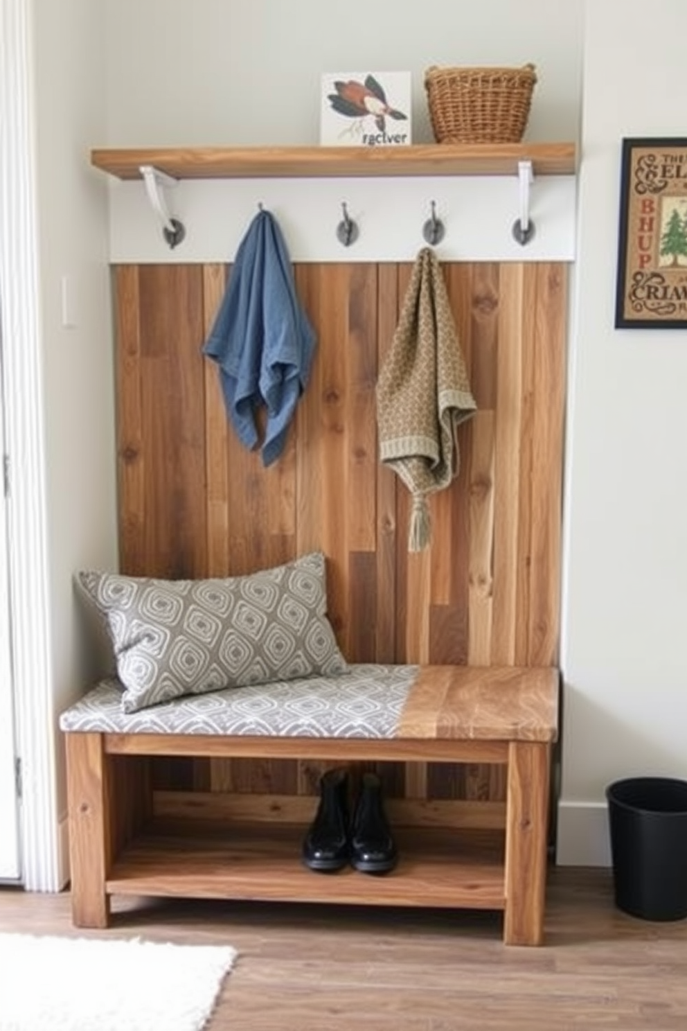 An industrial style bench with sturdy pipe legs is placed against a textured brick wall. The bench features a reclaimed wood top that adds warmth and character, complemented by a row of vintage hooks mounted above for hanging coats and bags. The floor is adorned with a durable, patterned tile that enhances the mudroom's functionality. Natural light streams in through a nearby window, illuminating the space and highlighting the unique design elements.