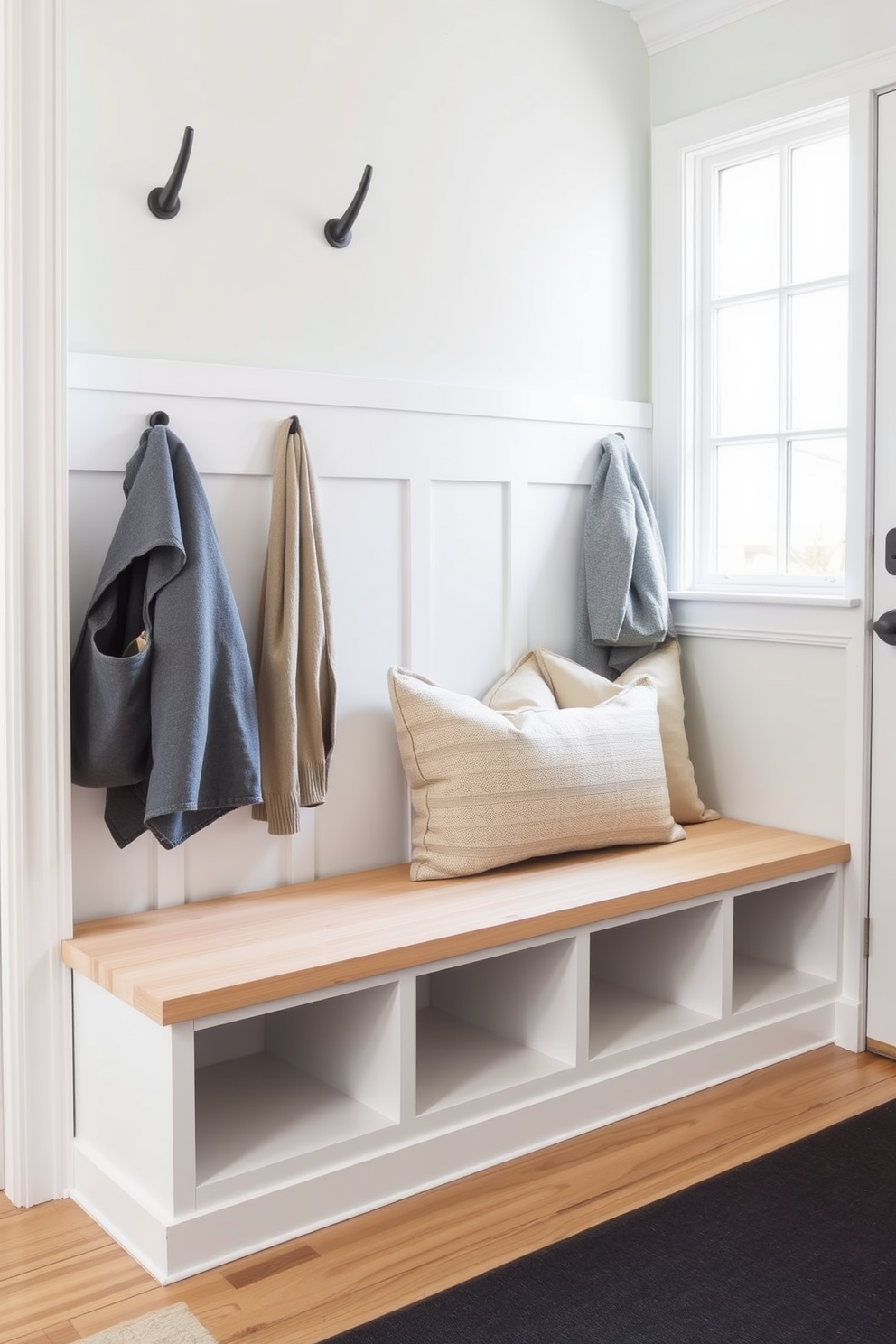 A charming farmhouse style bench is positioned against a shiplap wall, featuring a rustic wood finish that complements the overall aesthetic. The bench is adorned with plush cushions in neutral tones, providing both comfort and style for the mudroom space. Above the bench, hooks are mounted for hanging coats and bags, creating a functional yet inviting entryway. A woven basket sits beneath the bench, offering storage for shoes and accessories while enhancing the cozy farmhouse vibe.