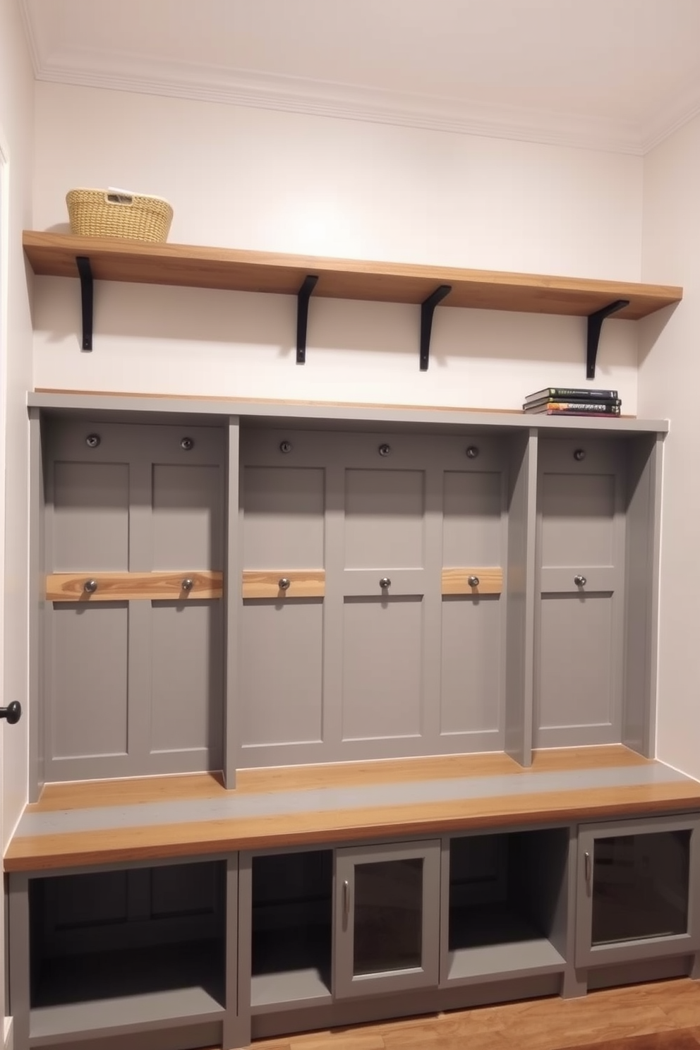 A functional mudroom featuring wall-mounted shelves above cubbies. The cubbies are designed with a mix of open and closed storage, painted in a soft gray color to complement the warm wood accents.