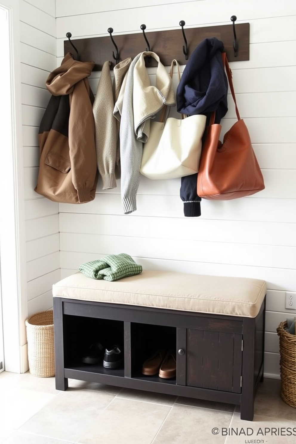 Cozy bench with storage underneath. The bench is upholstered in a soft fabric, and the storage compartment is accessible from the top, providing a practical solution for storing shoes and outdoor gear. The mudroom features a light color palette with shiplap walls and a durable tile floor. Hooks are installed above the bench for hanging coats and bags, creating an inviting and organized entryway.