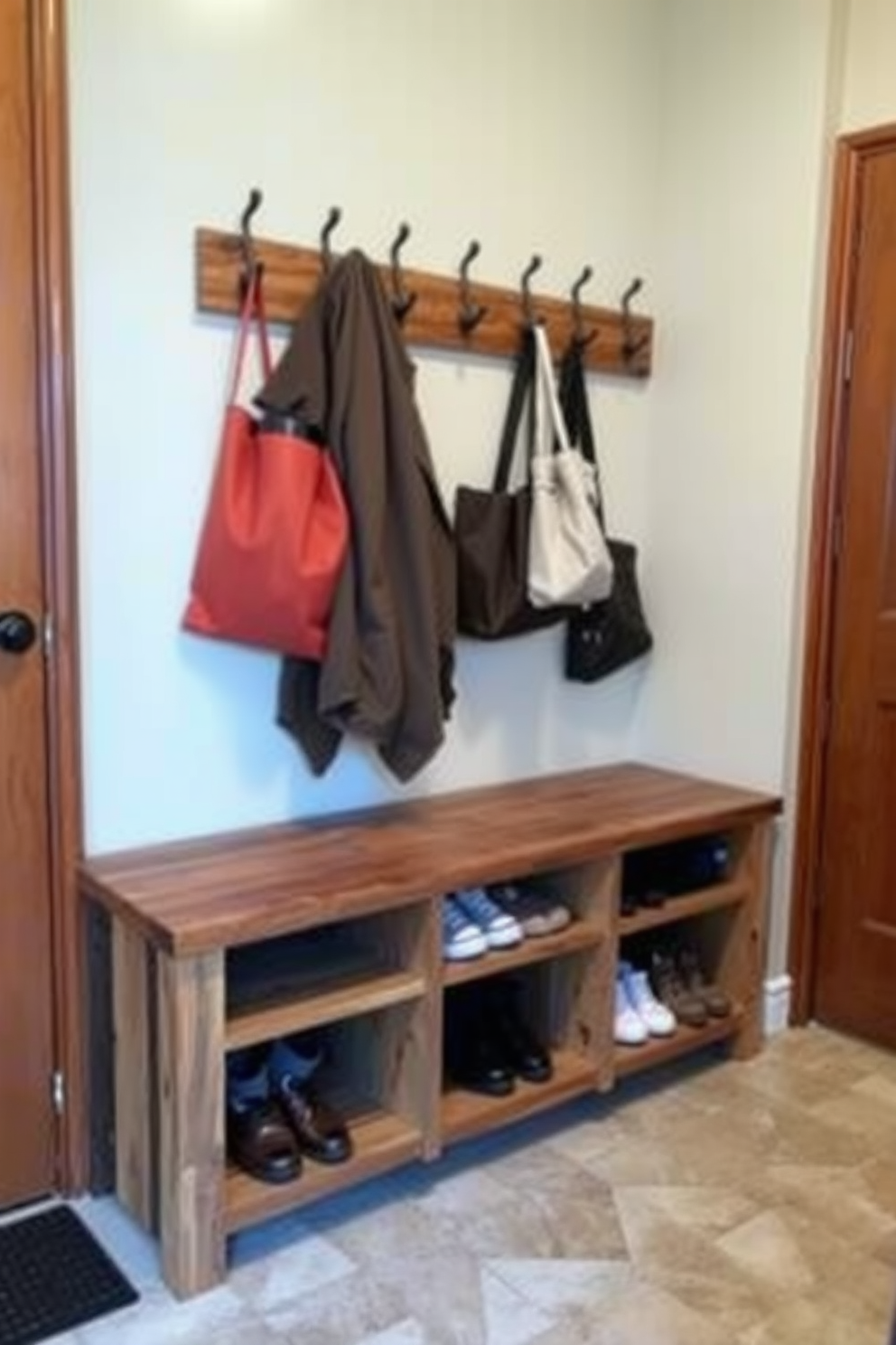 A functional mudroom featuring a hidden laundry hamper for convenience. The space includes built-in storage benches with hooks above for coats and bags, all designed in a soft gray color palette.