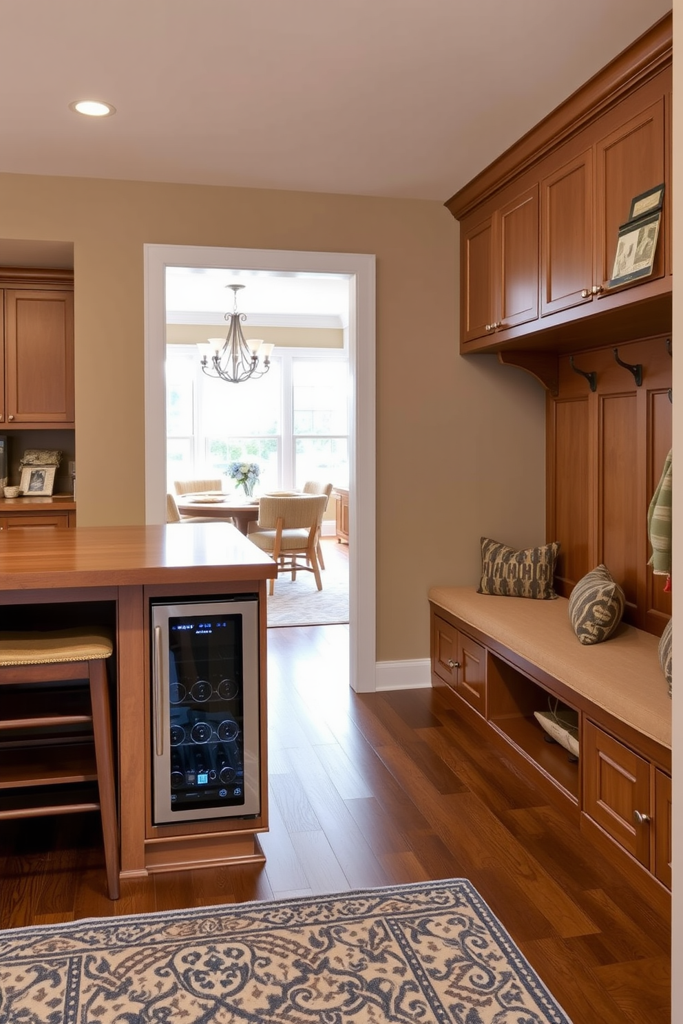 A functional island for extra workspace features a large wooden countertop with bar stools on one side. Underneath, there are open shelves for storage and a built-in wine cooler integrated into the cabinetry. The mudroom near the dining room includes a built-in bench with cushioned seating and hooks for hanging coats. The walls are painted in a warm neutral tone, complemented by a patterned rug on the floor for added texture.