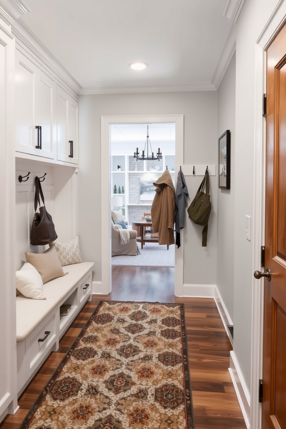 A welcoming mudroom adjacent to the family room features a built-in bench with ample storage beneath. Soft warm throw pillows in various textures are arranged on the bench to enhance comfort and invite relaxation.