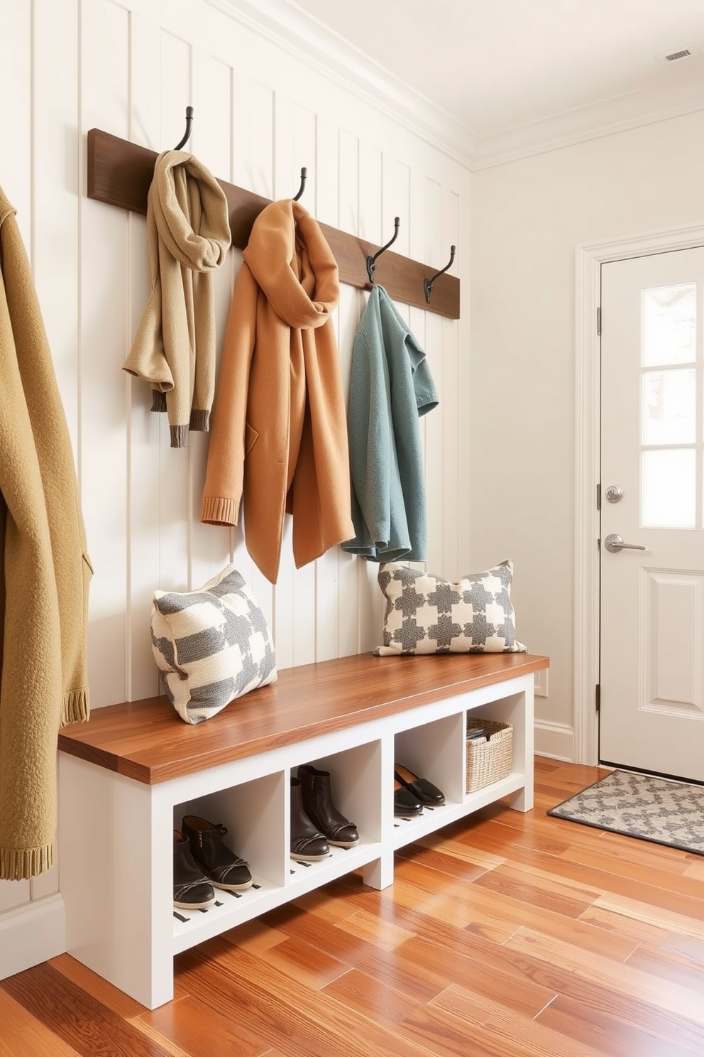 A cozy bench with storage underneath is placed against the wall in the mudroom near the garage. The bench is upholstered in a soft fabric and features a row of hooks above it for hanging jackets and bags.