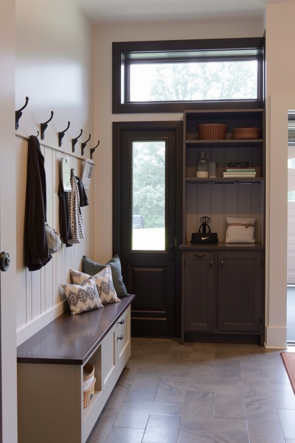 A functional drop zone for keys and mail is designed with a built-in bench and wall hooks for easy access. The space features a stylish cabinet for storage and a durable floor that can withstand heavy traffic. The mudroom near the garage is brightened by natural light streaming through a window. It includes a combination of open shelving for decorative items and closed storage for outdoor gear.