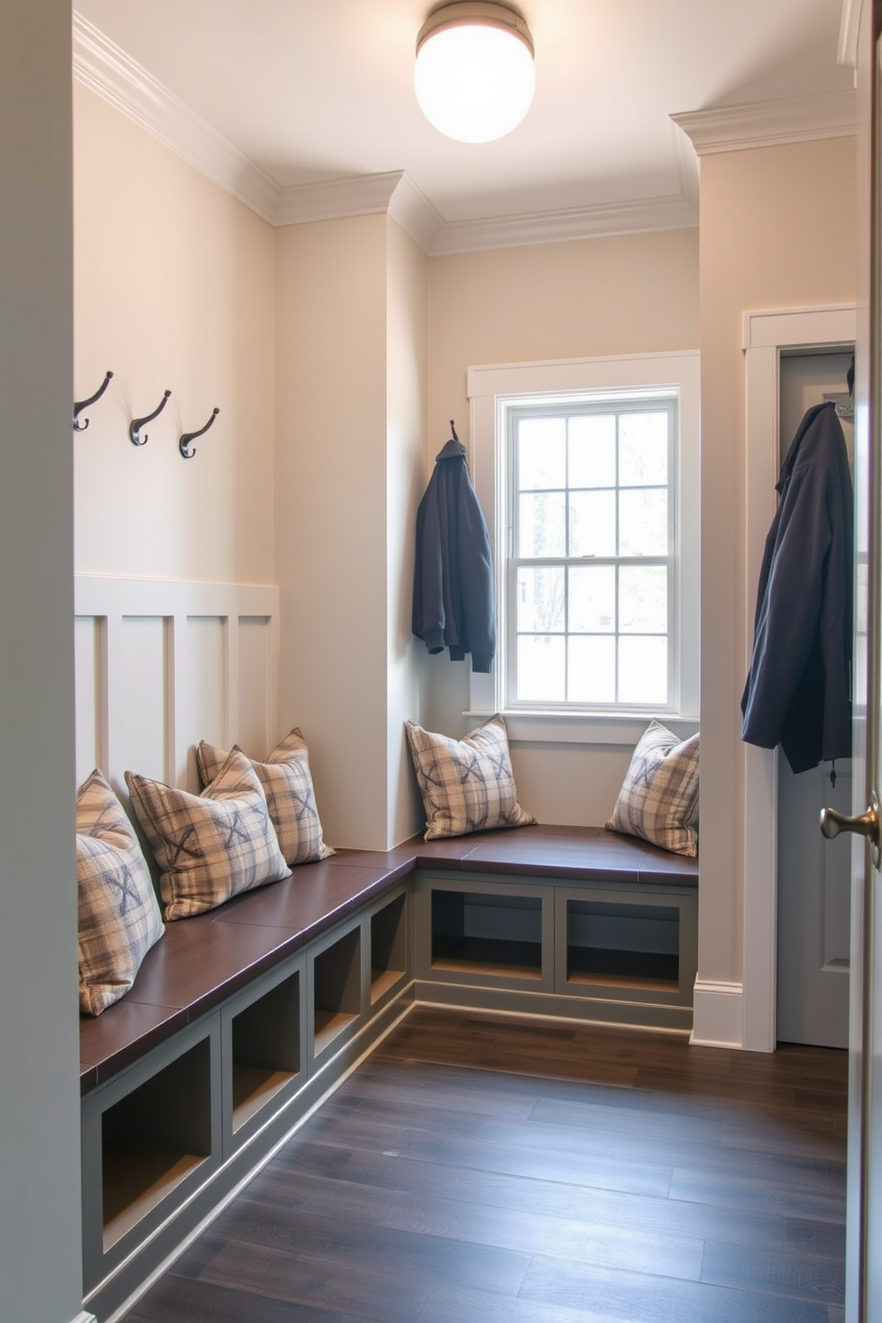 A cozy mudroom near the garage features built-in seating with plush cushions for added comfort. The walls are adorned with hooks for coats and a bench below, while natural light floods the space through a nearby window.