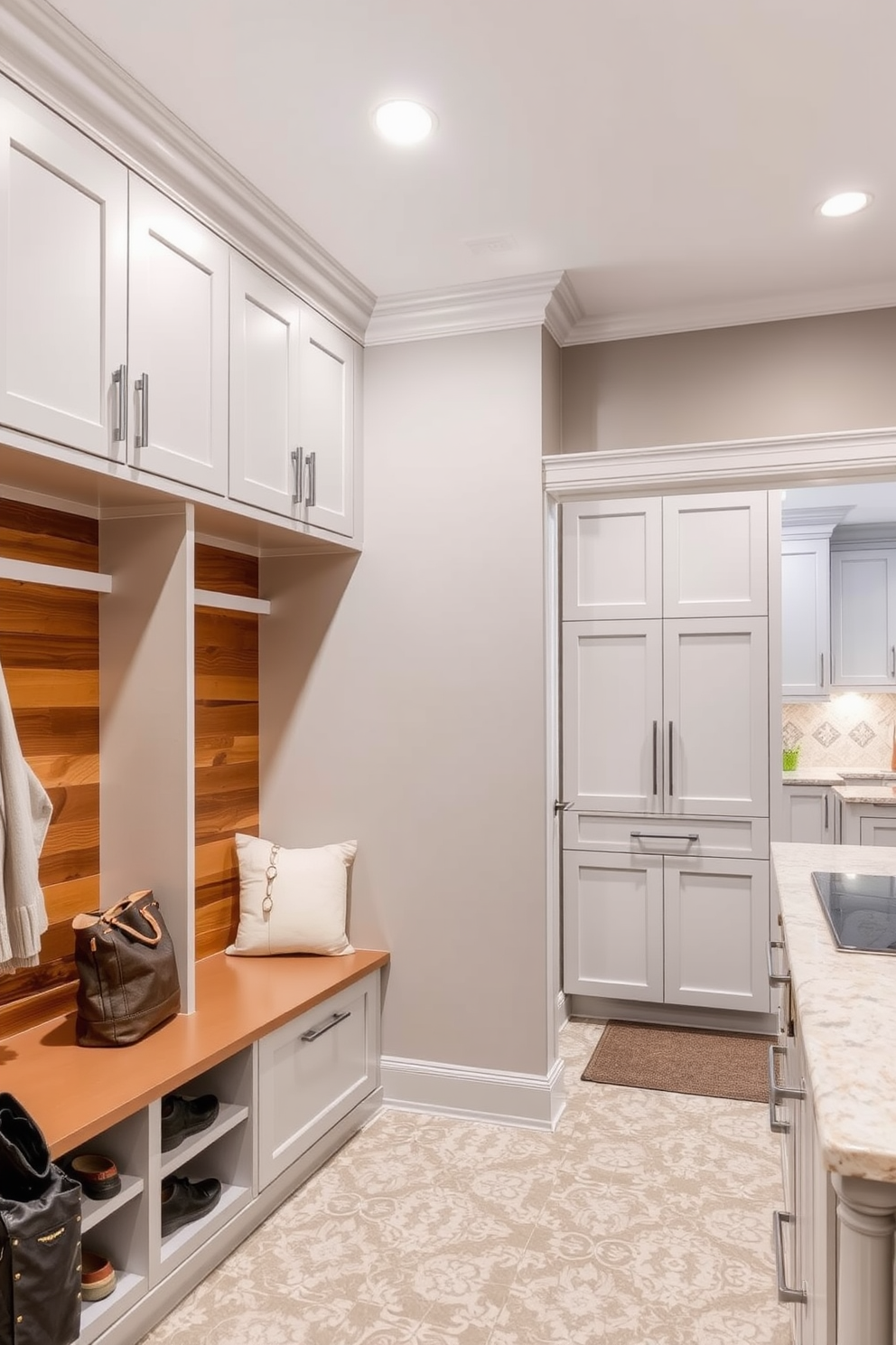 Recessed lighting illuminates the mudroom, creating a bright and welcoming atmosphere. The space features built-in storage cubbies with a sleek bench, perfect for shoes and bags. Adjacent to the kitchen, the mudroom showcases a stylish combination of functionality and aesthetics. Soft gray cabinetry complements the warm wood accents, while a patterned tile floor adds visual interest.