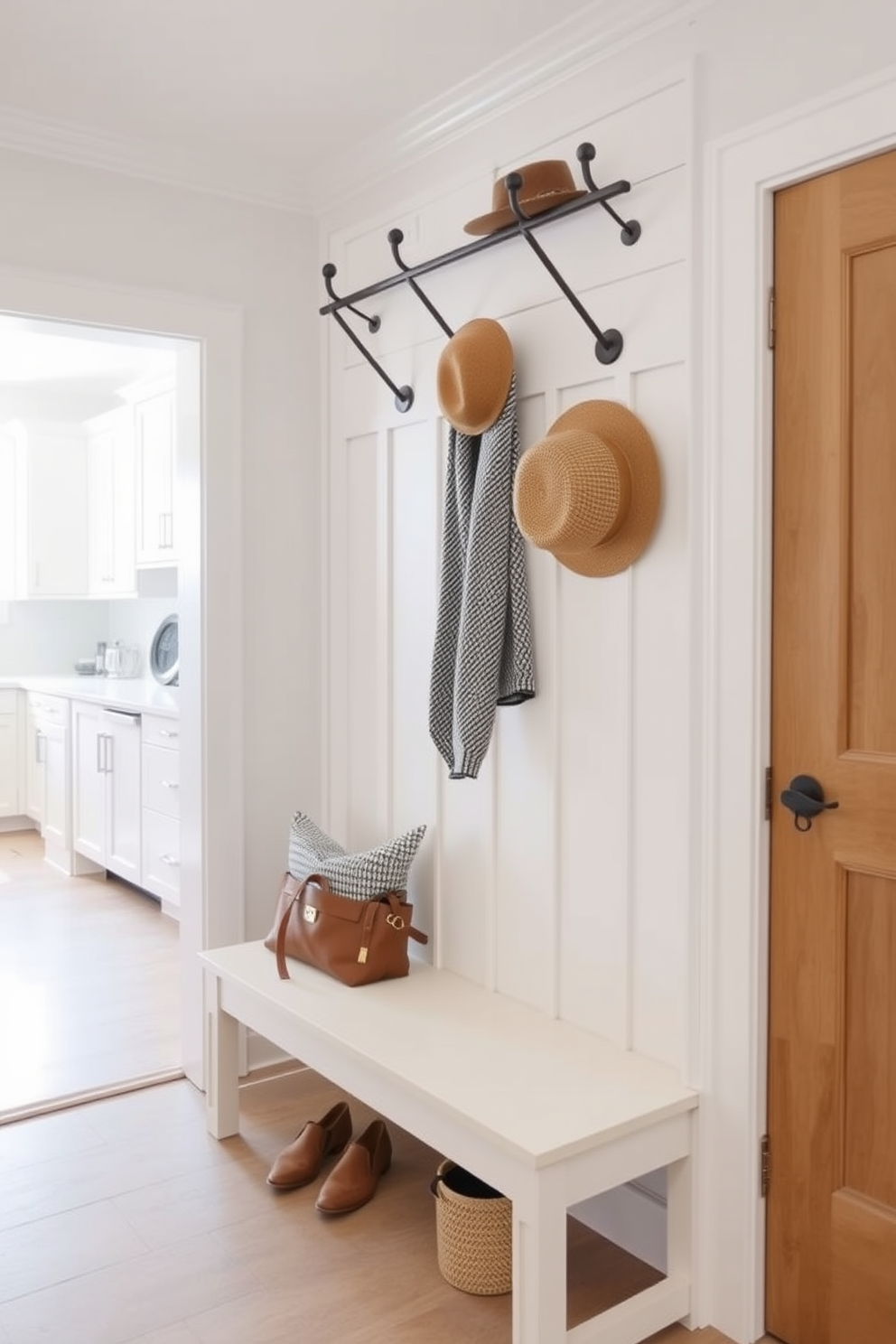 A welcoming mudroom design near the kitchen features a row of stylish wall hooks for coats and hats. The space is bright and airy with a light-colored bench below the hooks, providing both function and comfort.