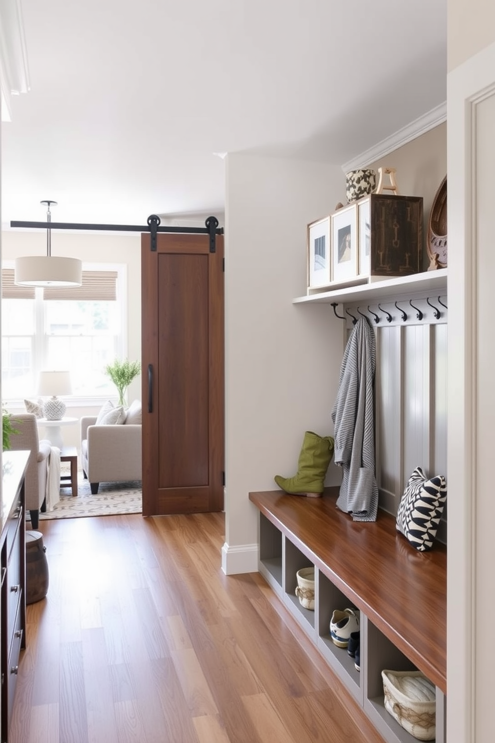 A stylish mudroom featuring a sliding barn door that opens into a spacious area. The walls are painted in a soft gray tone, and the floor is covered with rustic wooden planks. On one side, there are built-in benches with plush cushions and hooks above for hanging coats and bags. A large window allows natural light to flood in, creating a warm and inviting atmosphere. Adjacent to the living room, the design seamlessly blends with the overall decor of the home. Decorative elements like potted plants and a chic rug enhance the cozy feel of the space.