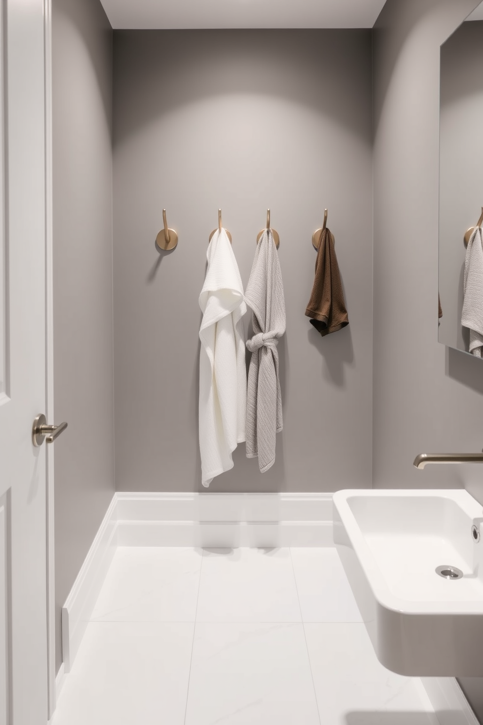 A narrow bathroom design featuring sleek wall-mounted hooks for towels and robes. The walls are painted in a soft gray tone, and the floor is adorned with large format white tiles for a spacious feel.