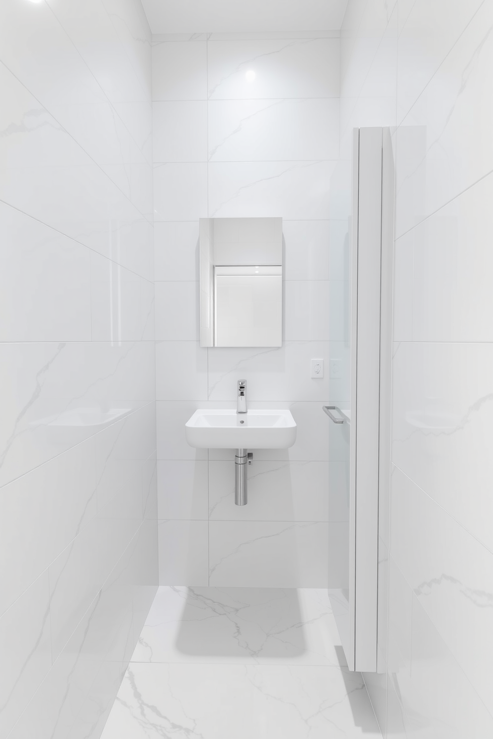 A narrow bathroom design featuring floor-to-ceiling tiling that enhances the sense of height. The tiles are a glossy white with subtle gray veining, creating a clean and modern look. A sleek, wall-mounted sink is positioned against one wall, paired with a minimalist mirror above it. On the opposite wall, a tall, slim storage cabinet provides ample space for toiletries while maintaining the streamlined aesthetic.