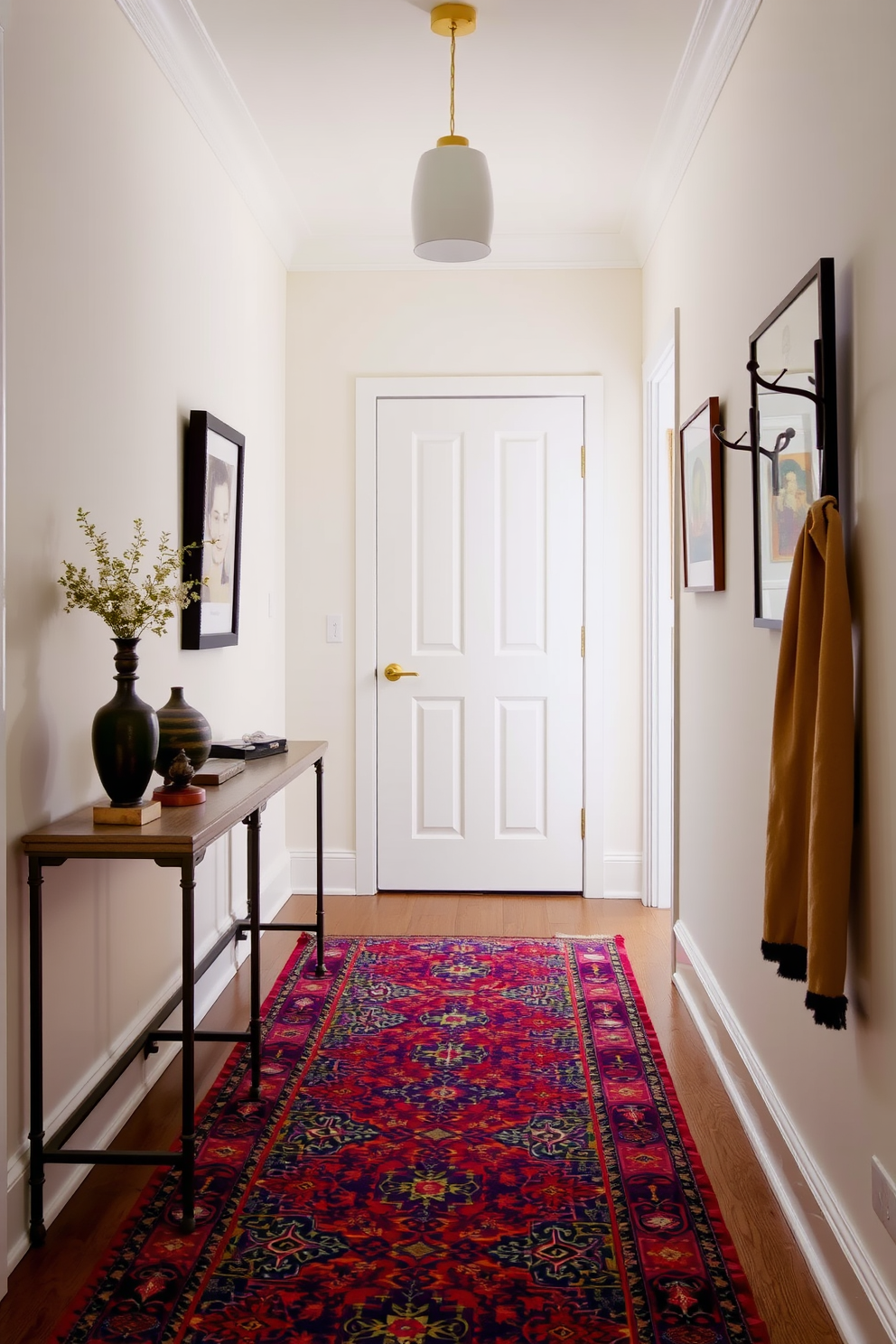 A colorful rug with intricate patterns lies at the center of a narrow entryway, adding warmth and vibrancy to the space. The walls are painted in a soft neutral tone, and a slim console table with decorative accents is positioned against one side. On the opposite wall, a series of framed artwork adds visual interest, while a stylish coat rack provides functionality. Soft lighting from a pendant fixture illuminates the entryway, creating an inviting atmosphere.