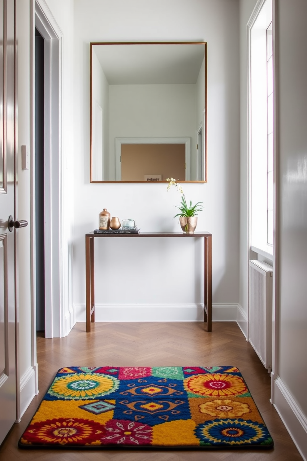 A colorful door mat with vibrant patterns and textures welcomes guests into the home. The mat features shades of blue, yellow, and red, creating an inviting atmosphere right at the entrance. The narrow foyer is designed with a sleek console table against one wall, adorned with decorative items and a small potted plant. A large mirror above the table reflects light, making the space feel larger and more open.